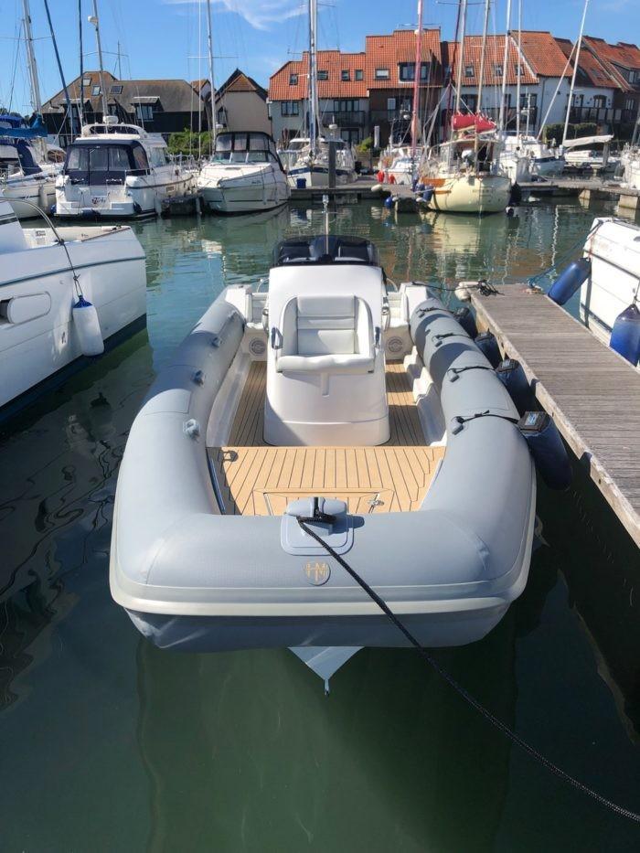 2020 HM Powerboats 7.1 RIB docked in a marina, surrounded by other boats.