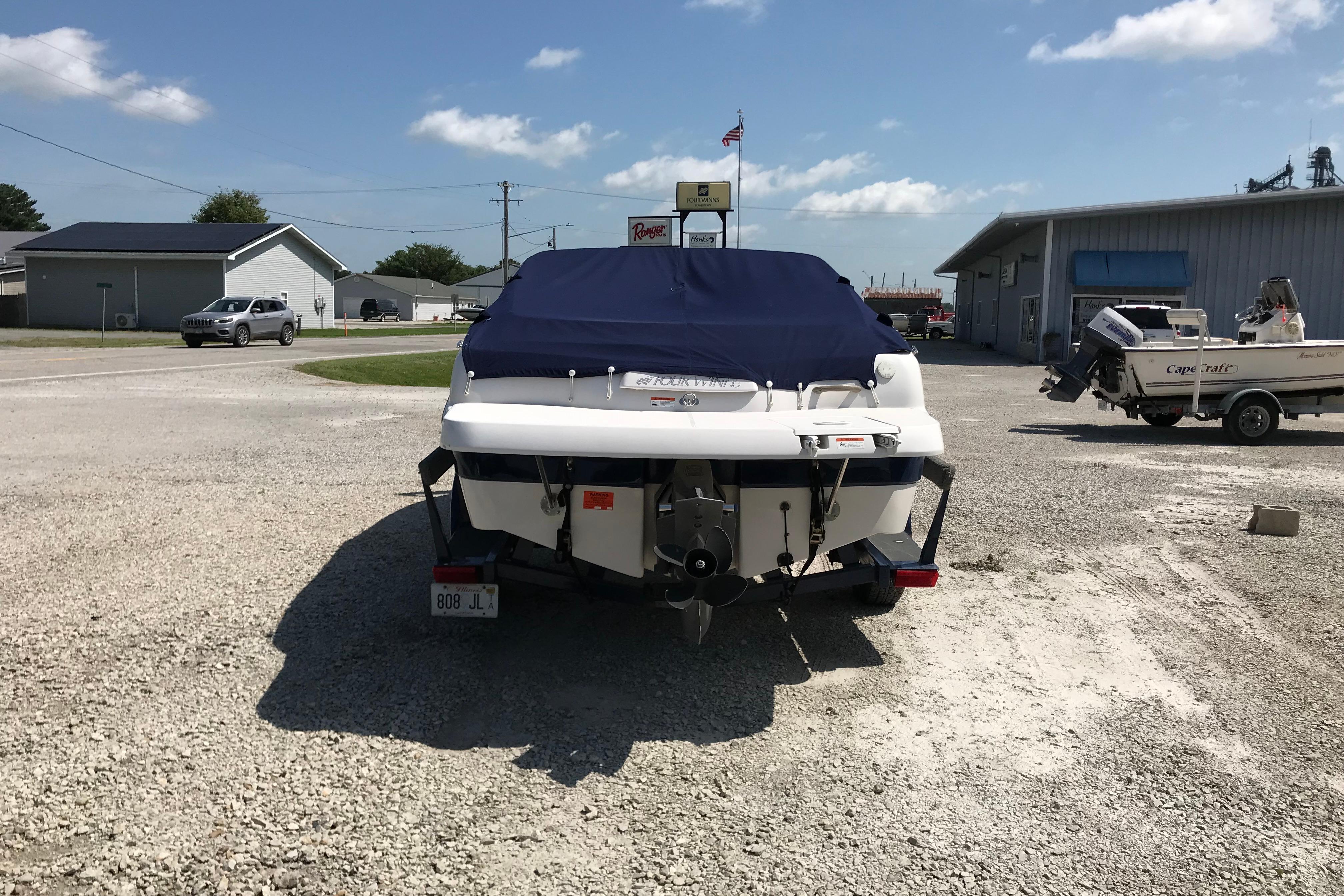 2005 Four Winns 180 Horizon FS boat with cover, parked on gravel lot.