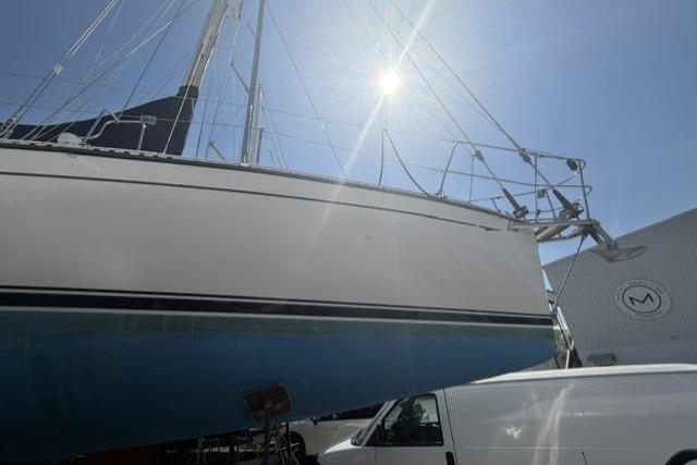 Sailboat Saga 43, 2002 model, docked under bright sun with a van nearby.