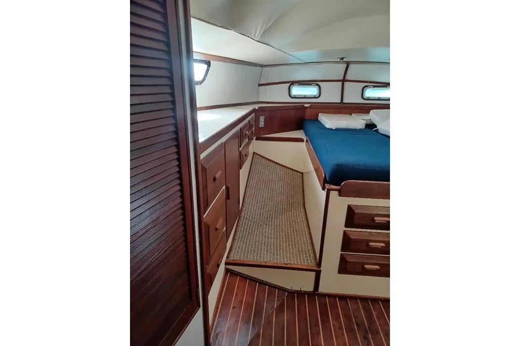 1977 Morgan Out Island 51 yacht interior with wooden cabinetry and blue bedding.