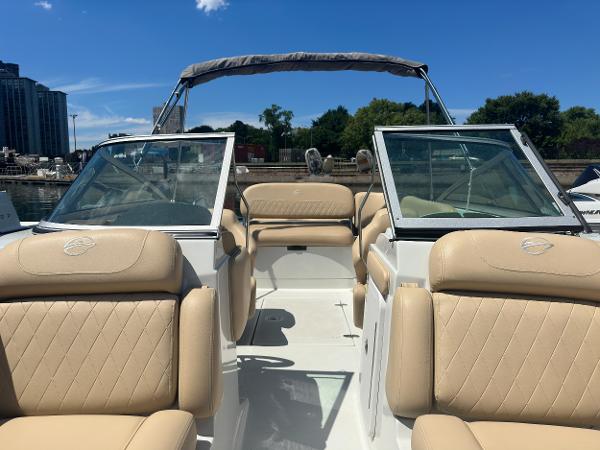 2023 Crownline 215 XS boat with beige seating and open deck under clear blue sky.