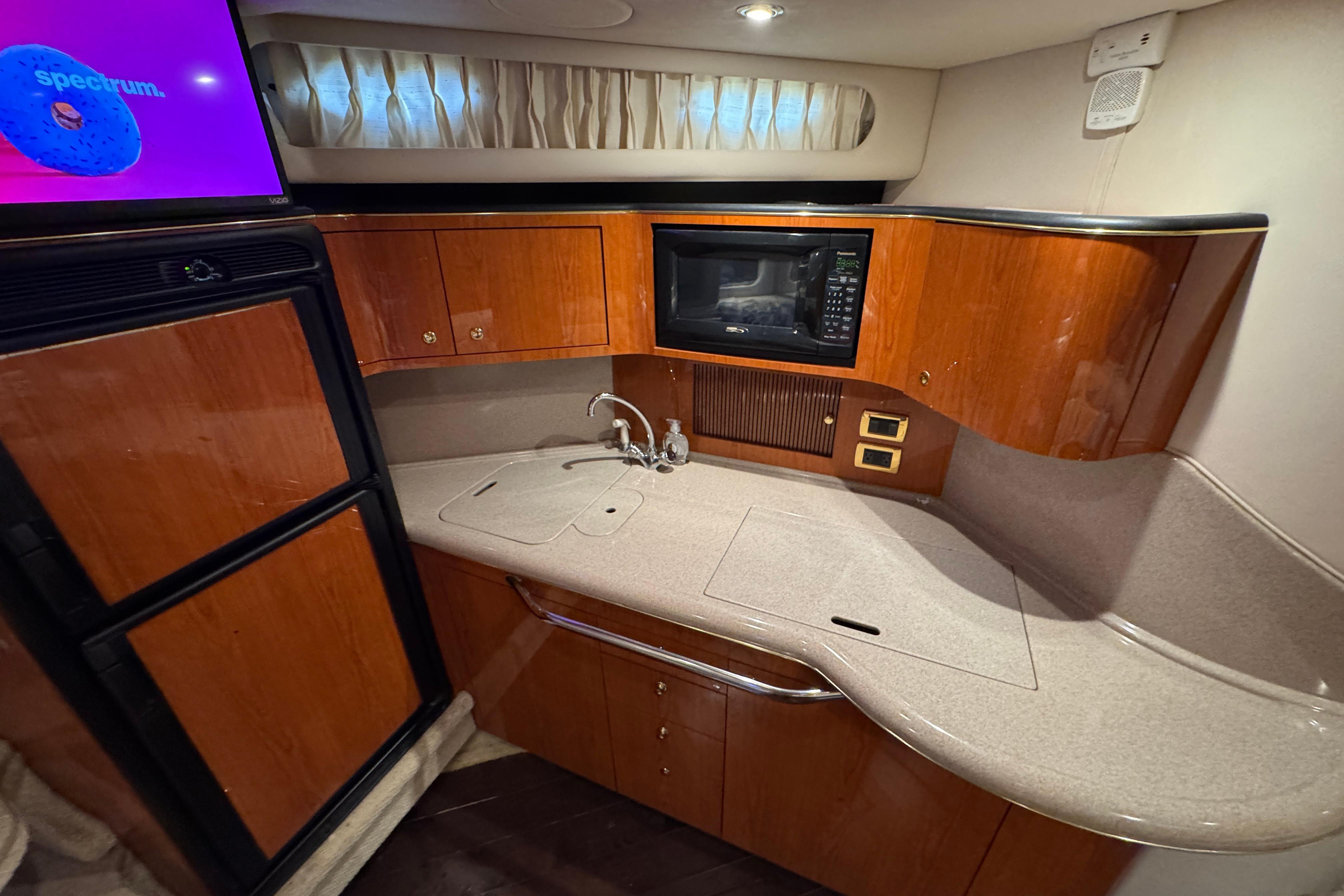 Luxurious 2001 Sea Ray 380 Sundancer yacht kitchen with wood cabinetry and modern appliances.