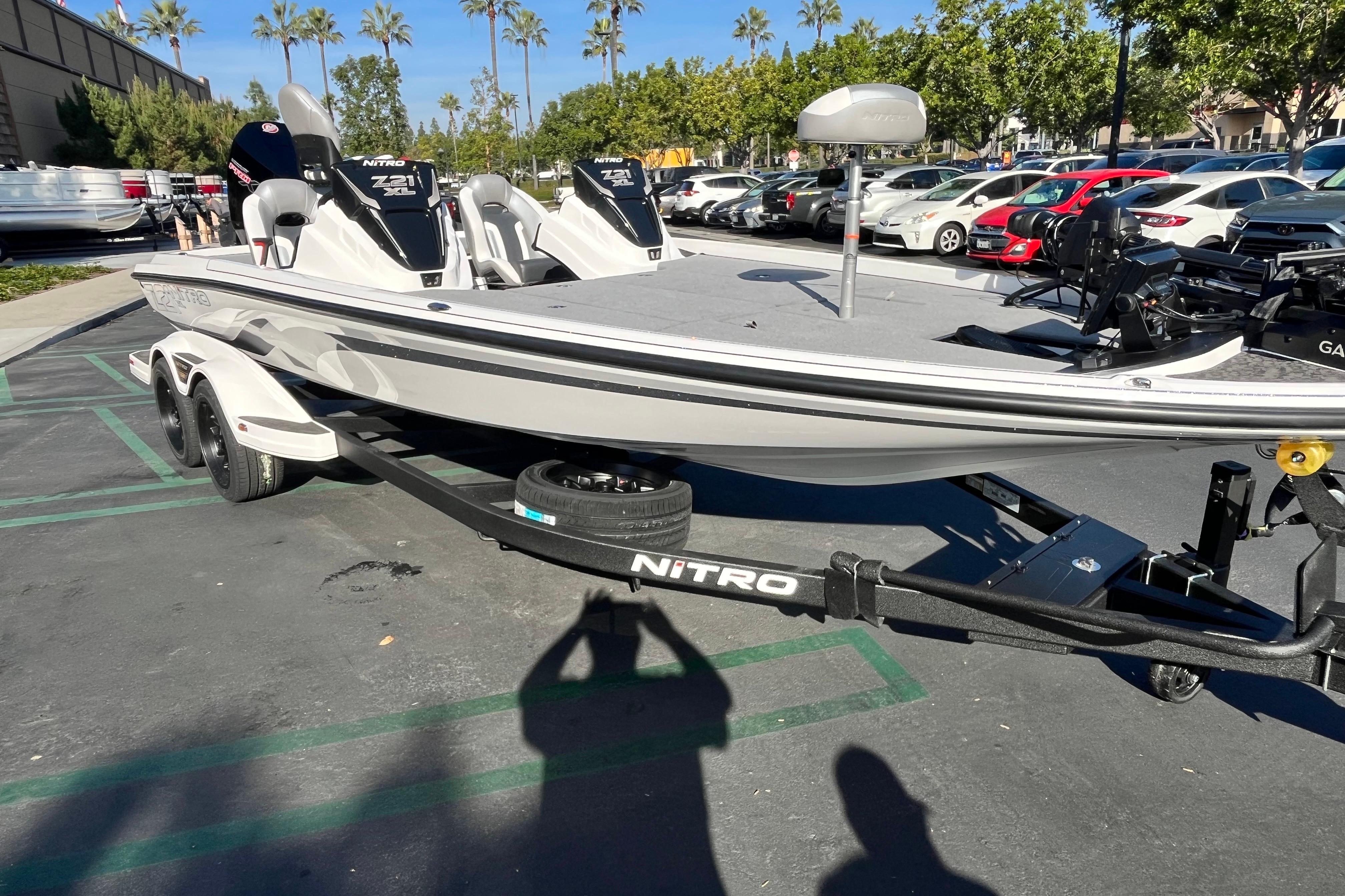 2026 Nitro Z21 XL Pro boat on trailer in parking lot, surrounded by cars and trees.