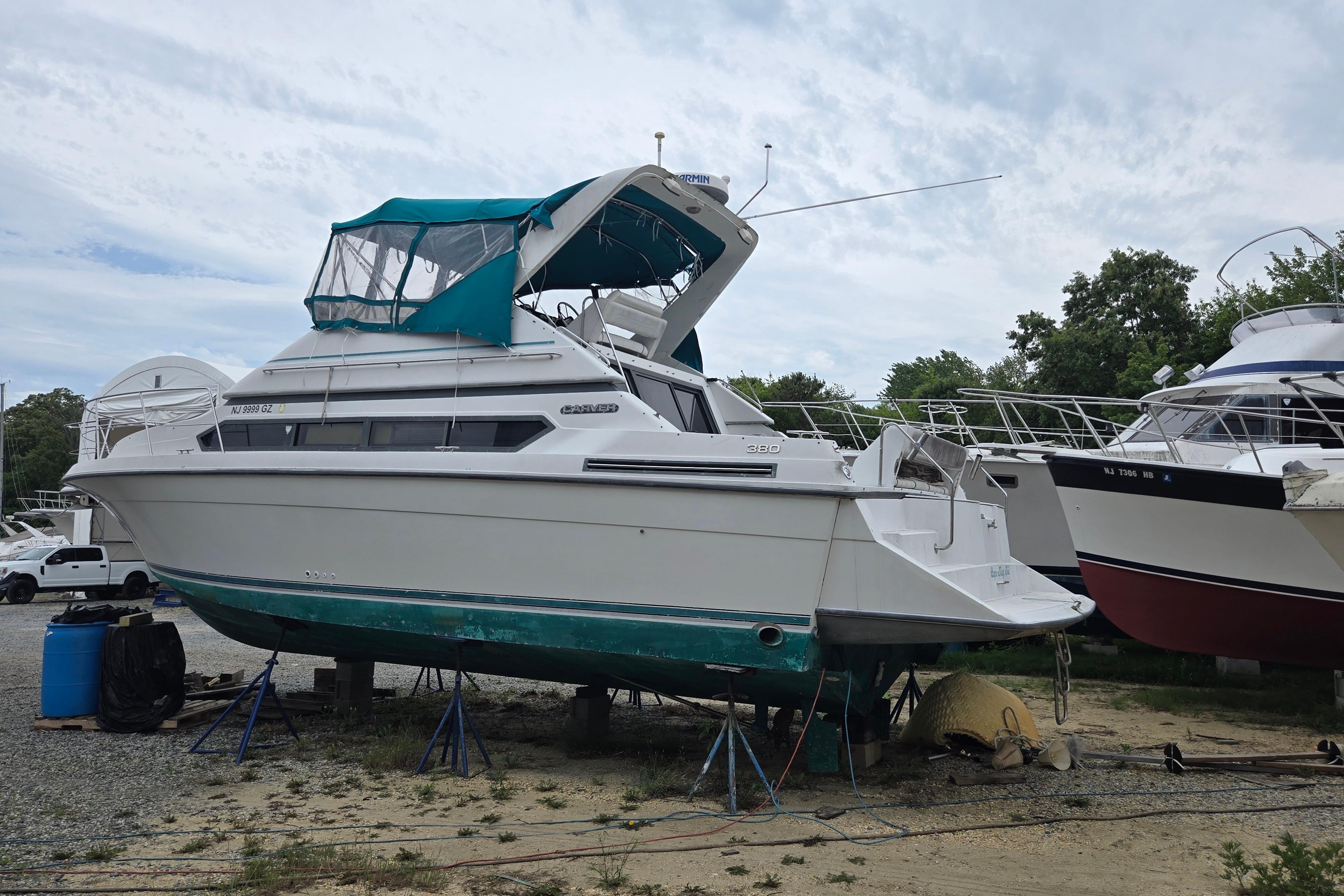 1994 Carver 380 Santego yacht on stands, with teal canopy, in a boatyard.