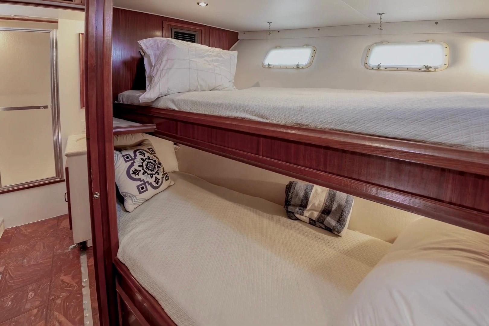 Bunk beds in 1980 Hatteras 70 Motor Yacht cabin with wooden accents and porthole windows.