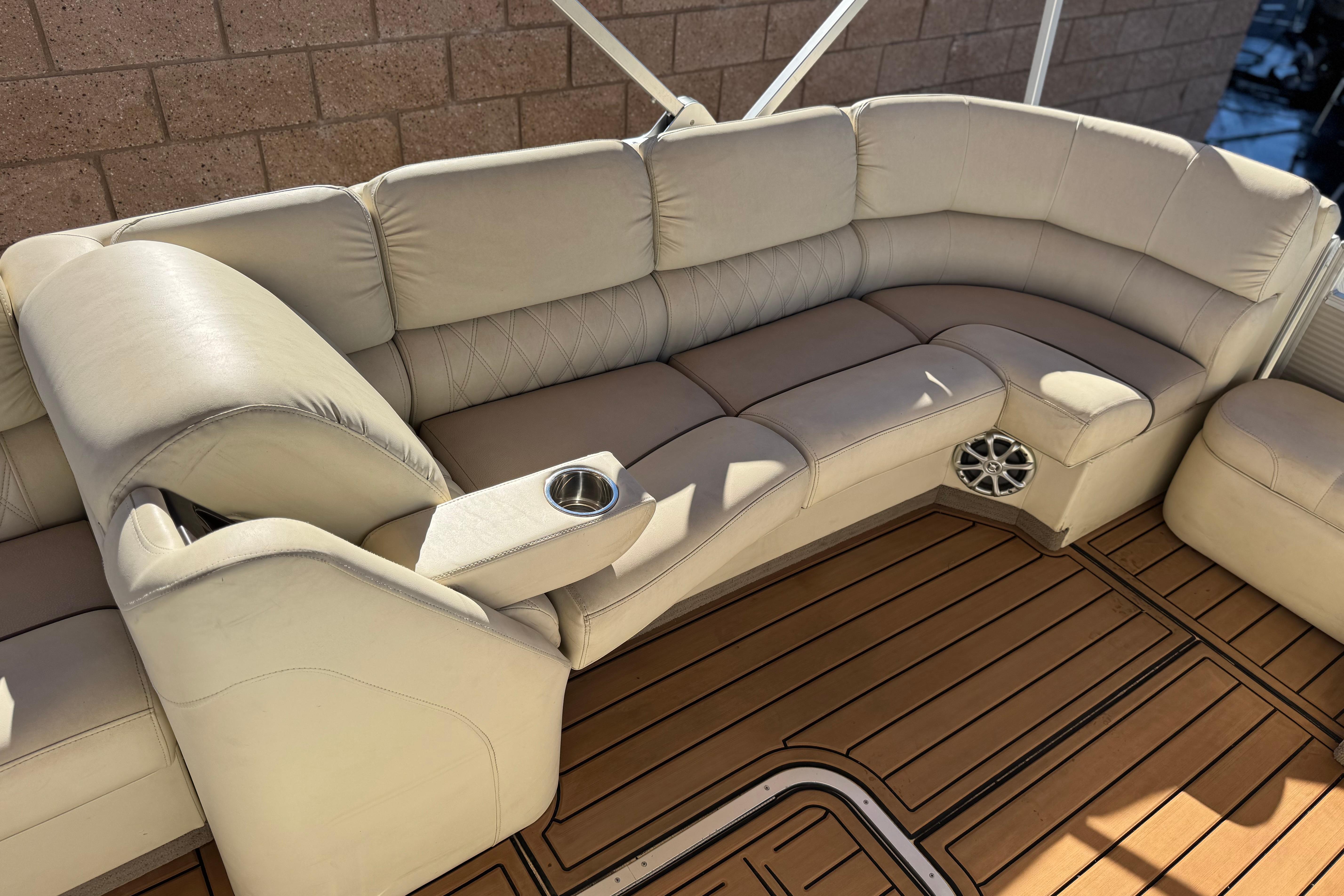 Luxurious seating on 2013 Bennington 2575QCW I/O boat with tan upholstery and wood-style flooring.