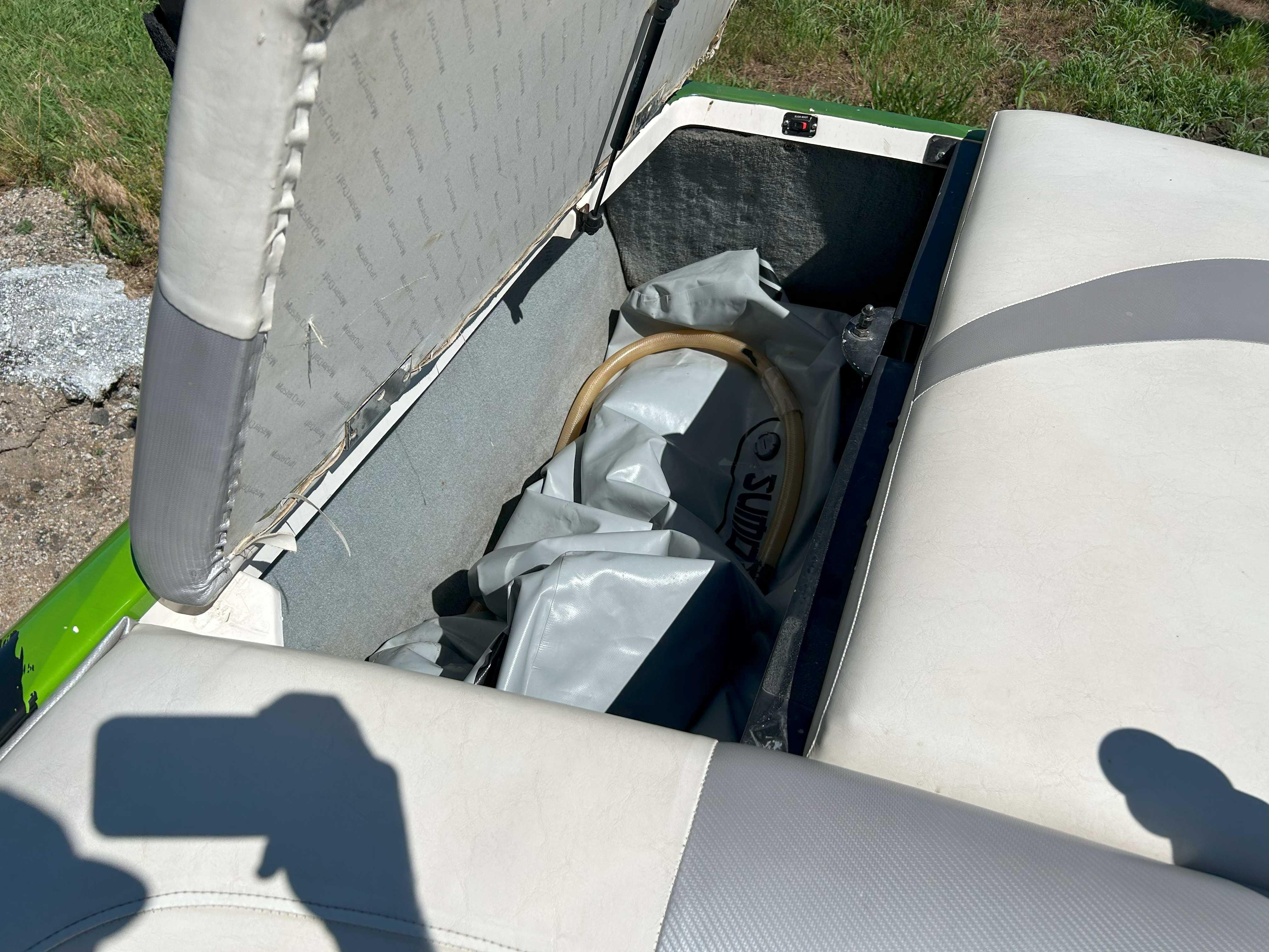 Open storage compartment in a 2002 MasterCraft XStar boat with interior items visible.