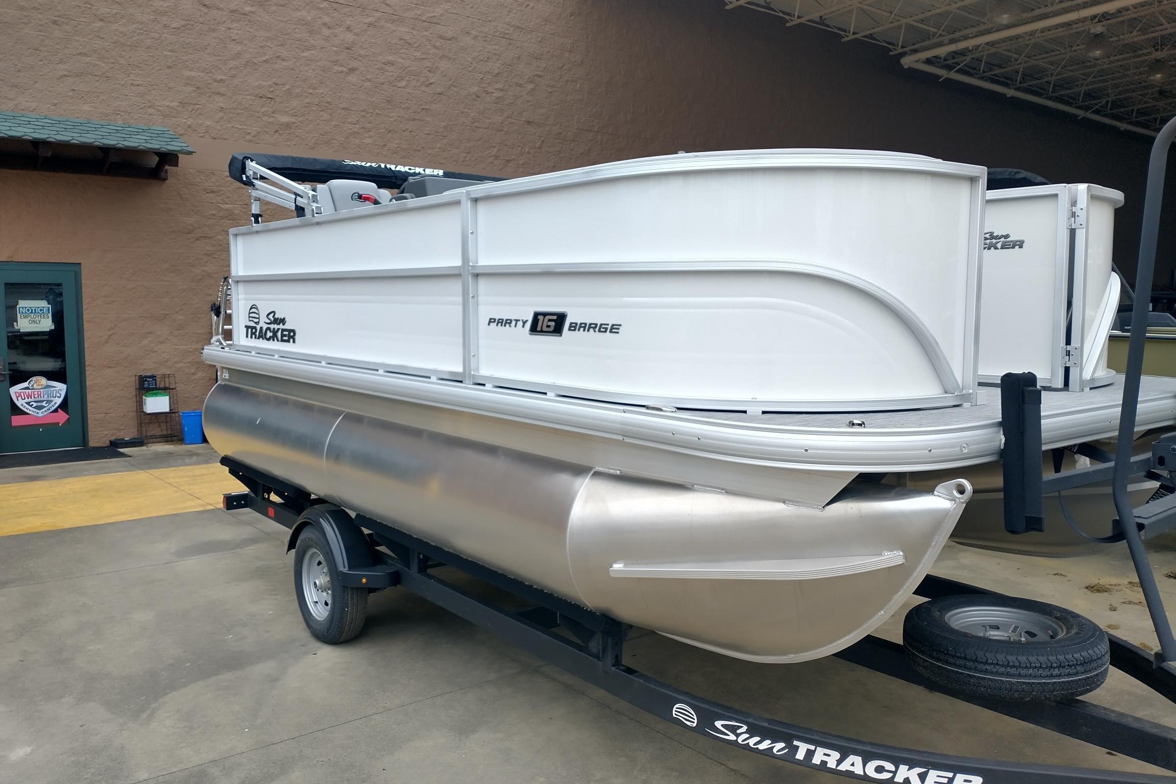 2026 Sun Tracker Party Barge 16 DLX pontoon boat on trailer, parked outdoors.