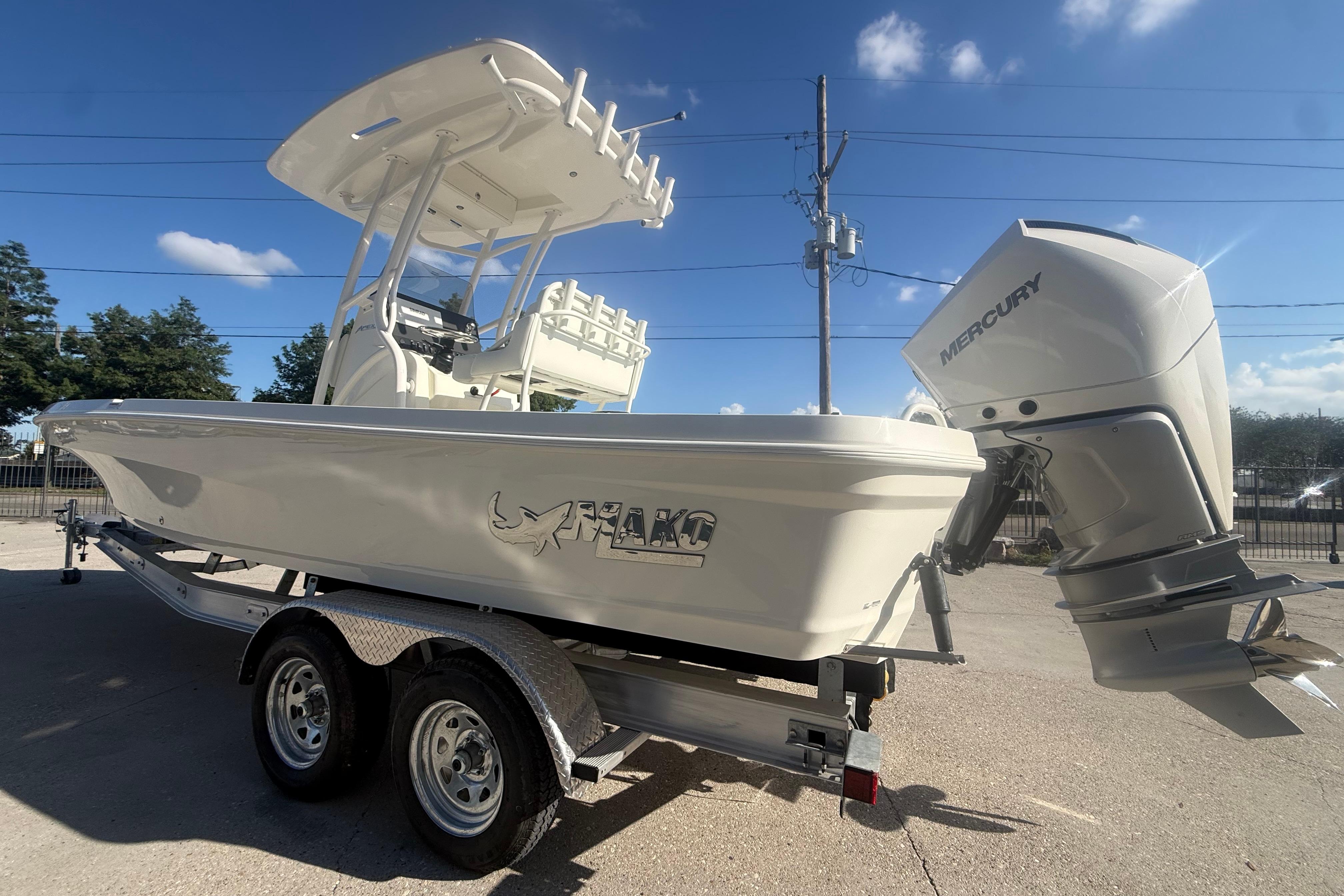 2026 Mako 24 APEX boat with Mercury engine on trailer, under clear blue sky.