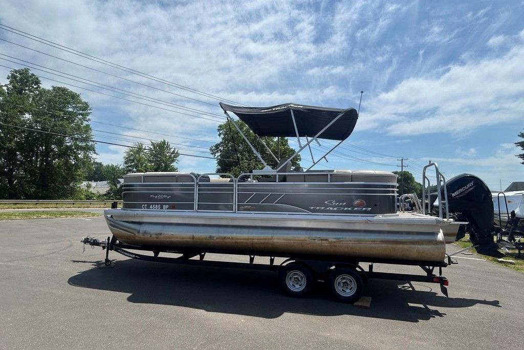 2023 Sun Tracker Party Barge 22 DLX pontoon boat on trailer under blue sky.