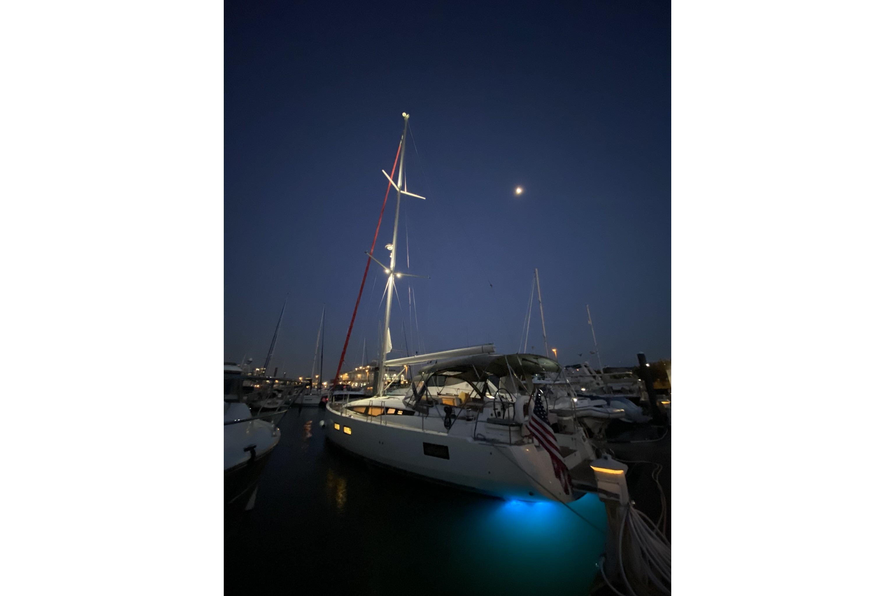 Sailboat Jeanneau 51 (2018) docked at night with illuminated deck and mast.