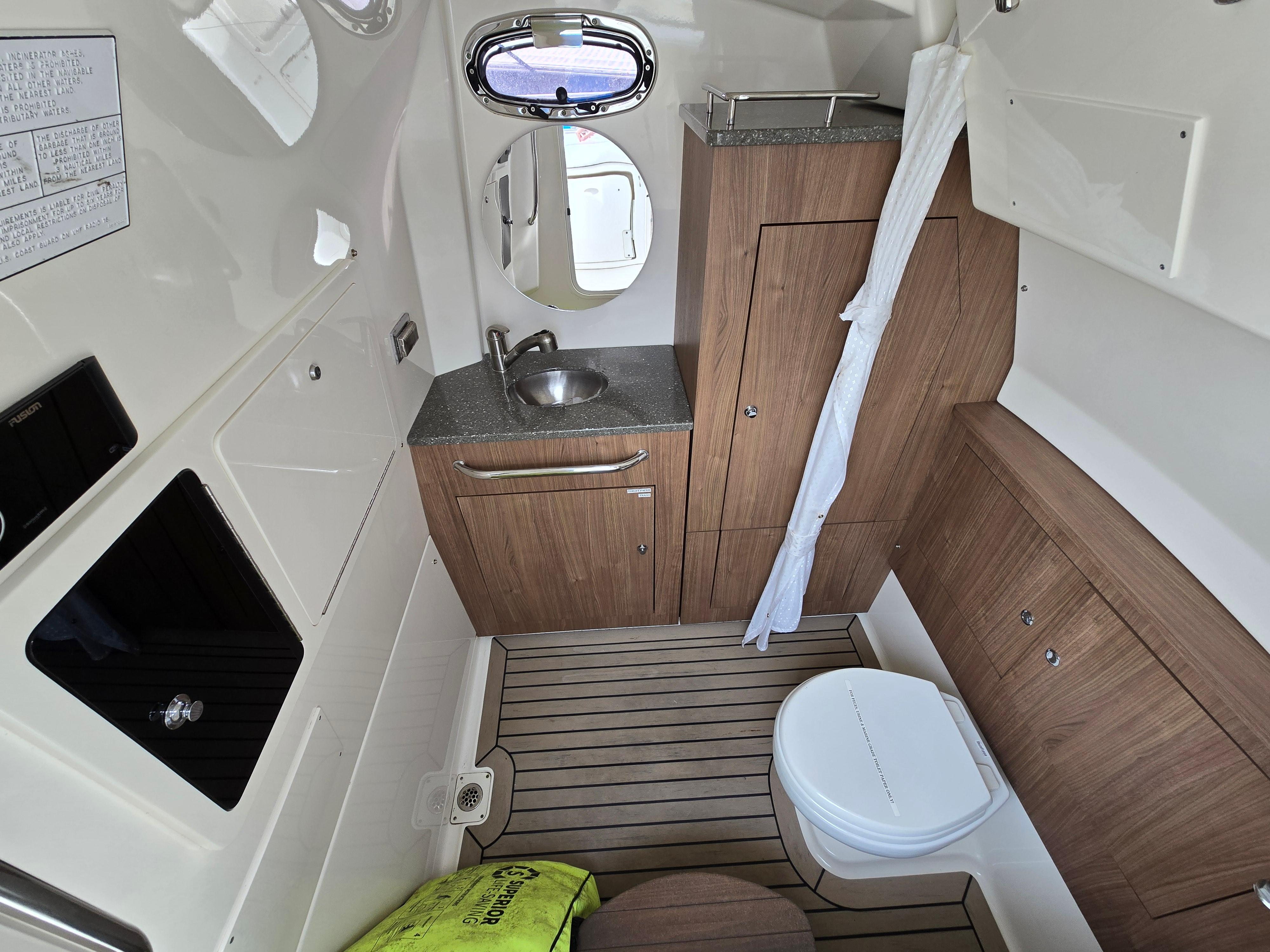 2015 Boston Whaler 350 Outrage cabin interior with sink, toilet, and wood cabinetry.