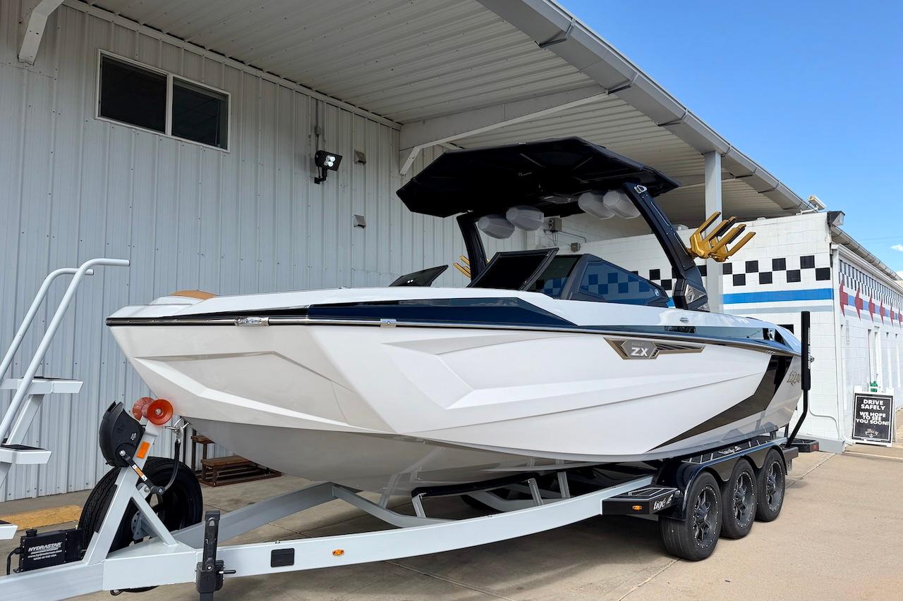 2025 Tigé Ultré 25ZX boat on trailer, parked outside a building.