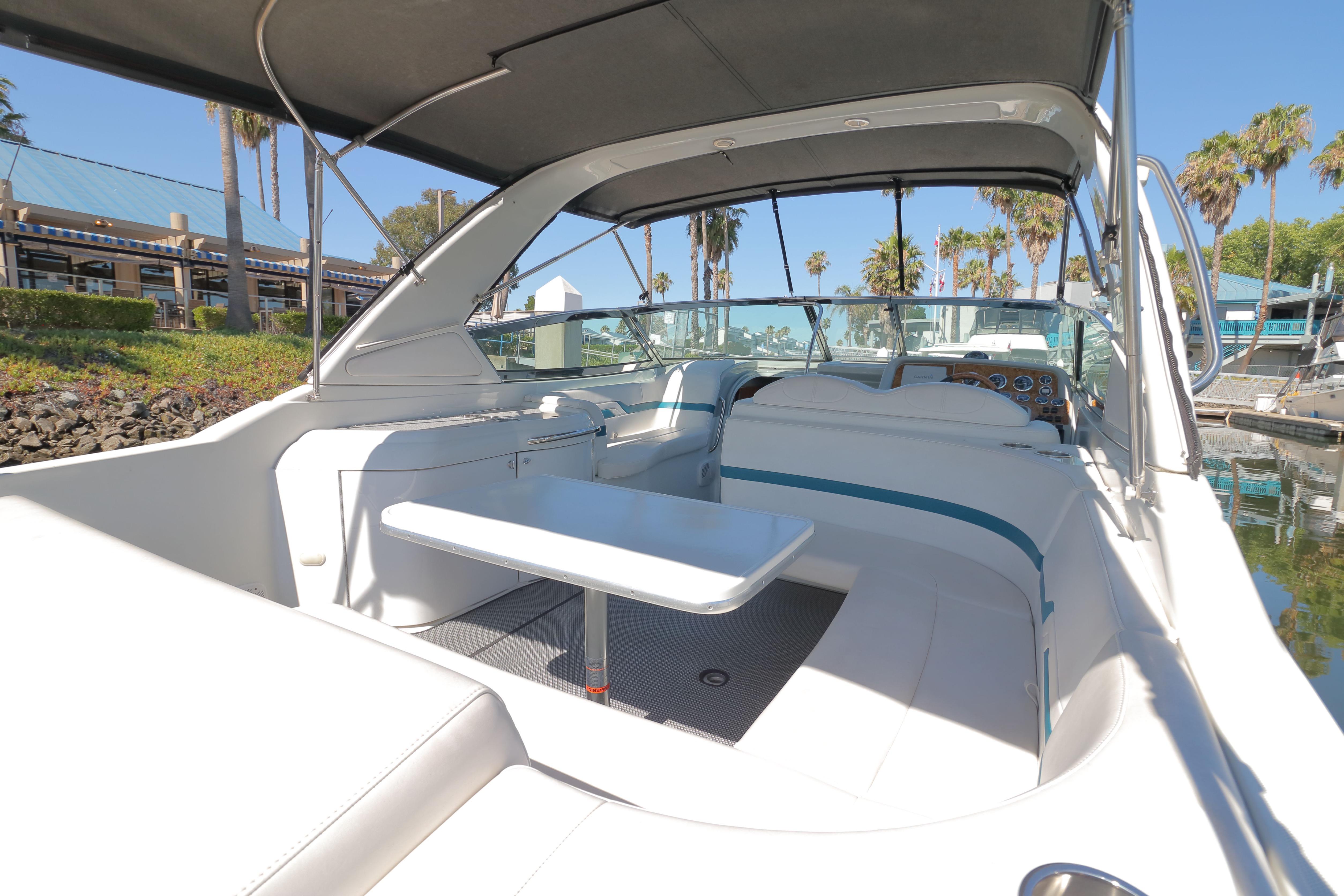2006 Formula 330 Sun Sport boat interior with seating and table, docked near palm trees.