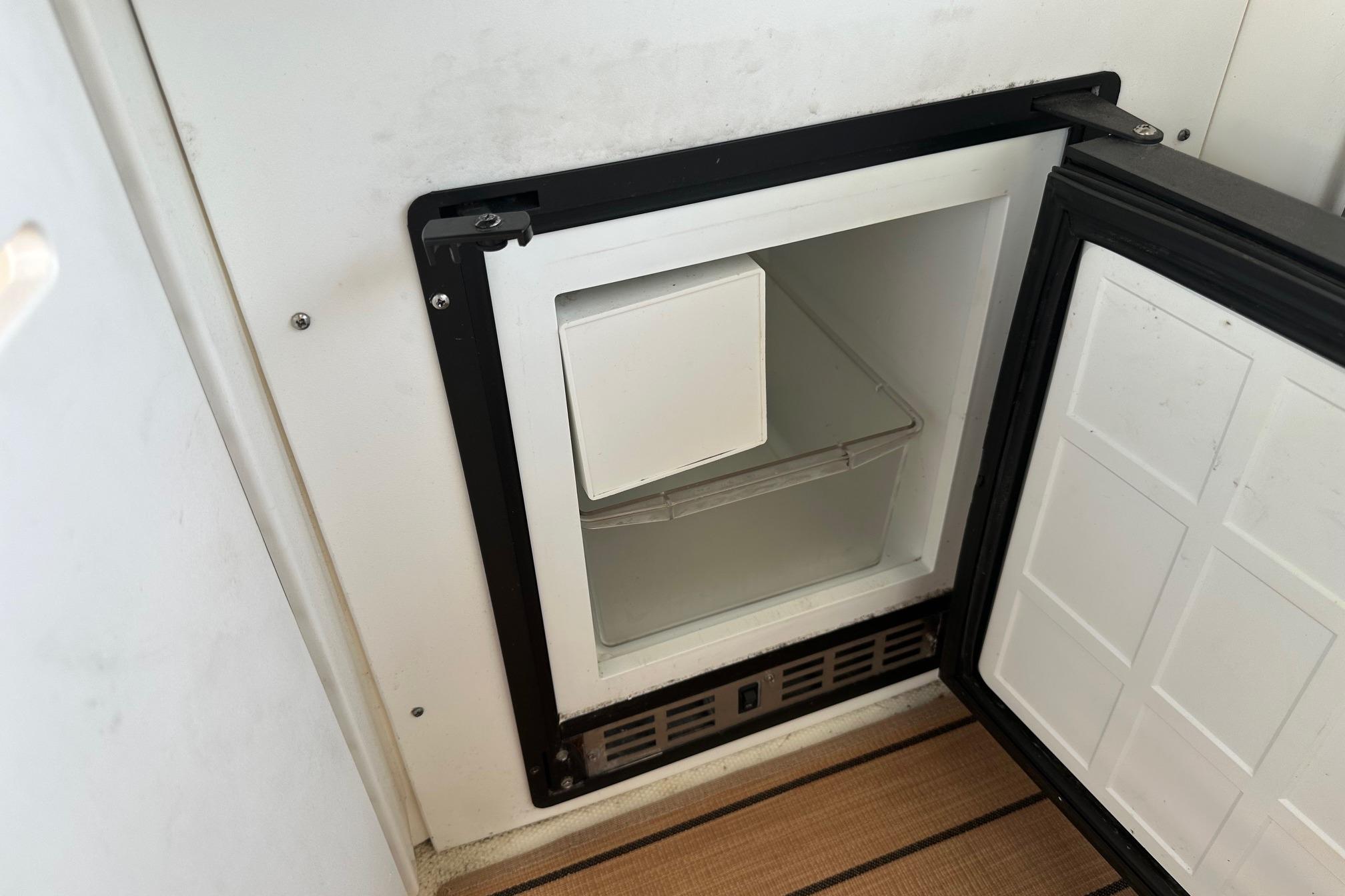 Open mini fridge on 2001 Sea Ray 410 Sundancer boat, showing interior storage space.