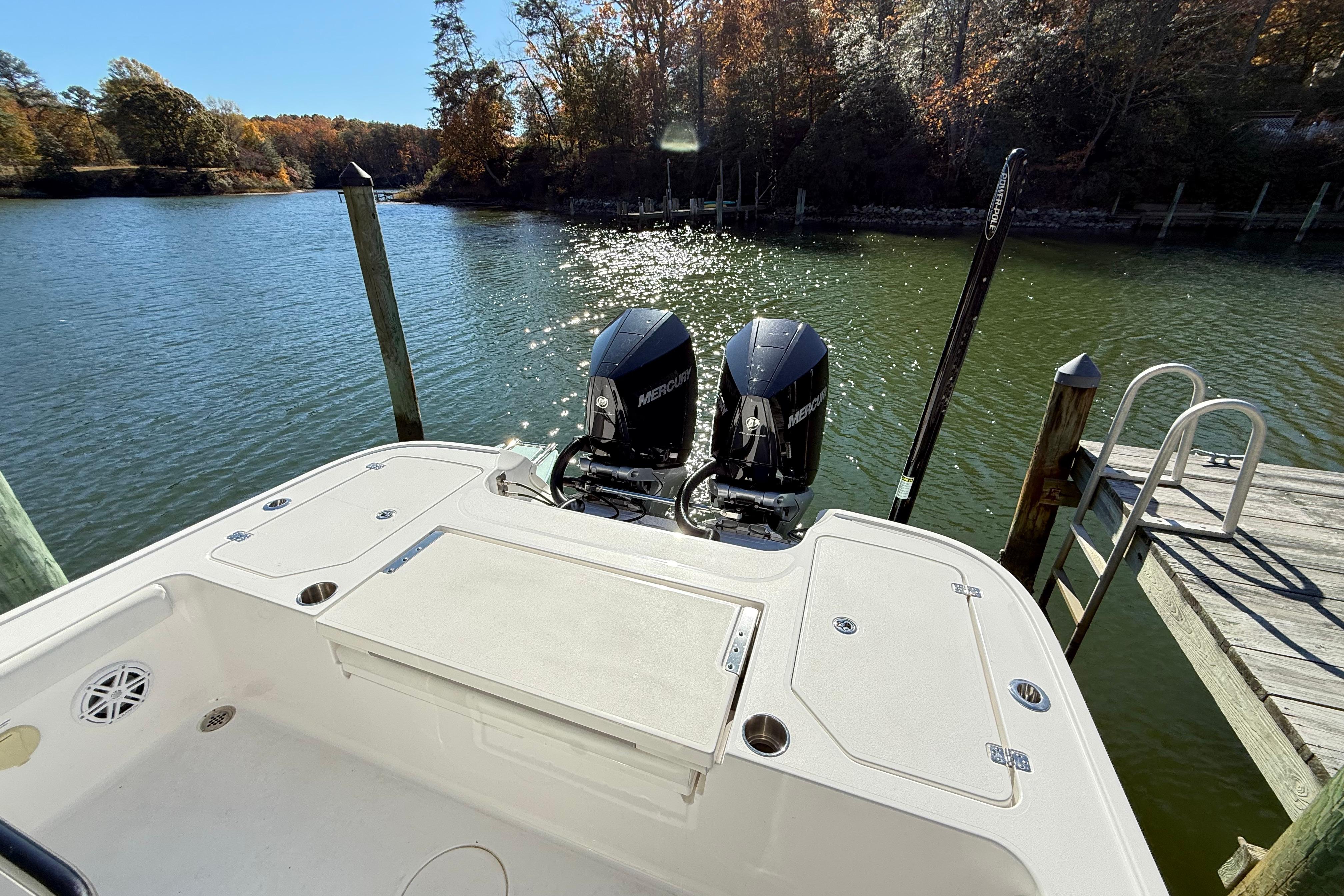 2023 Caymas 281 HB boat with dual Mercury engines docked by a serene lake.