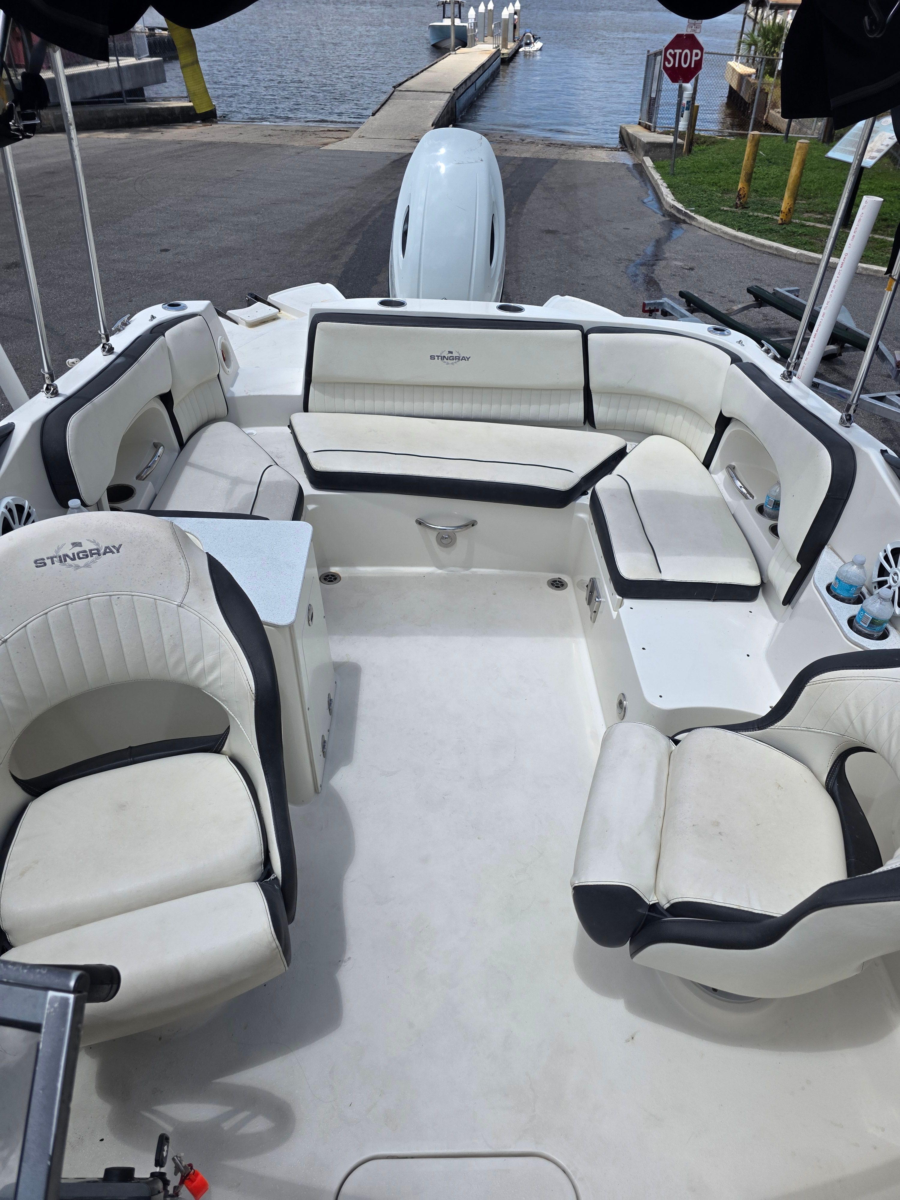 A Stingray 231 DC boat with white and black seating, docked at a calm harbor.