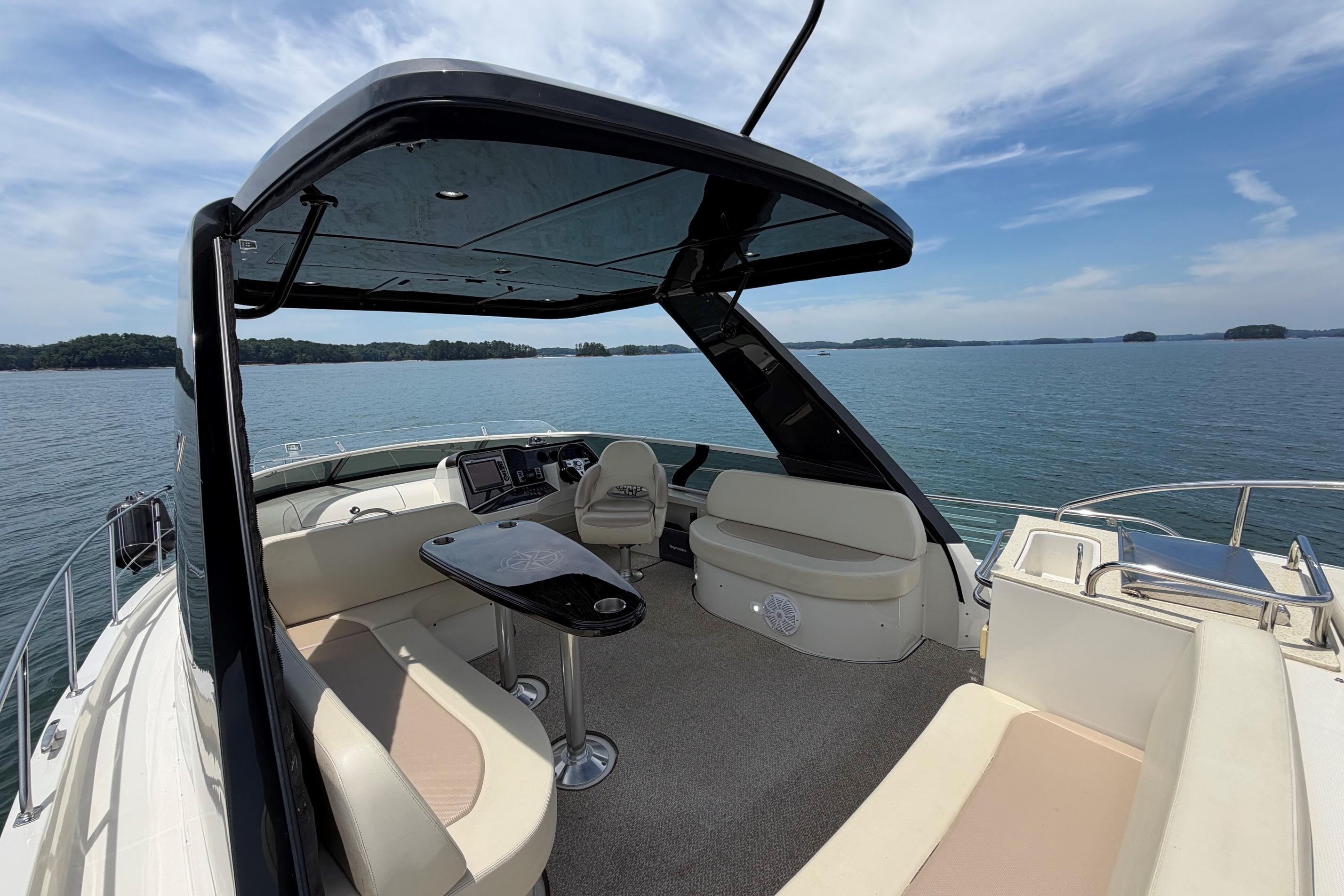 2011 Carver 44 Sojourn yacht interior with seating, table, and helm, overlooking serene waters.