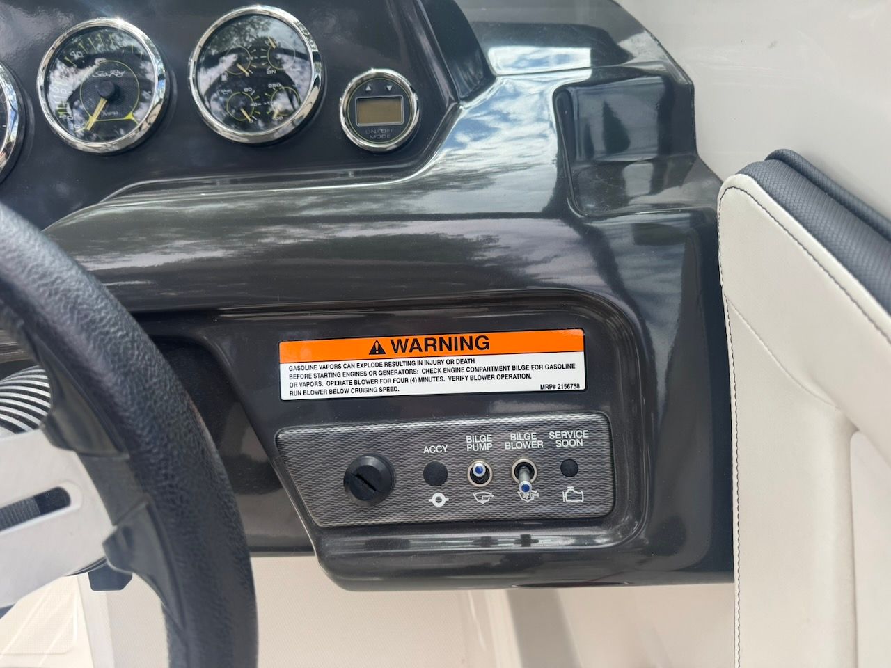 Close-up of a 2016 Sea Ray SPX 190 Outboard dashboard with a warning label.