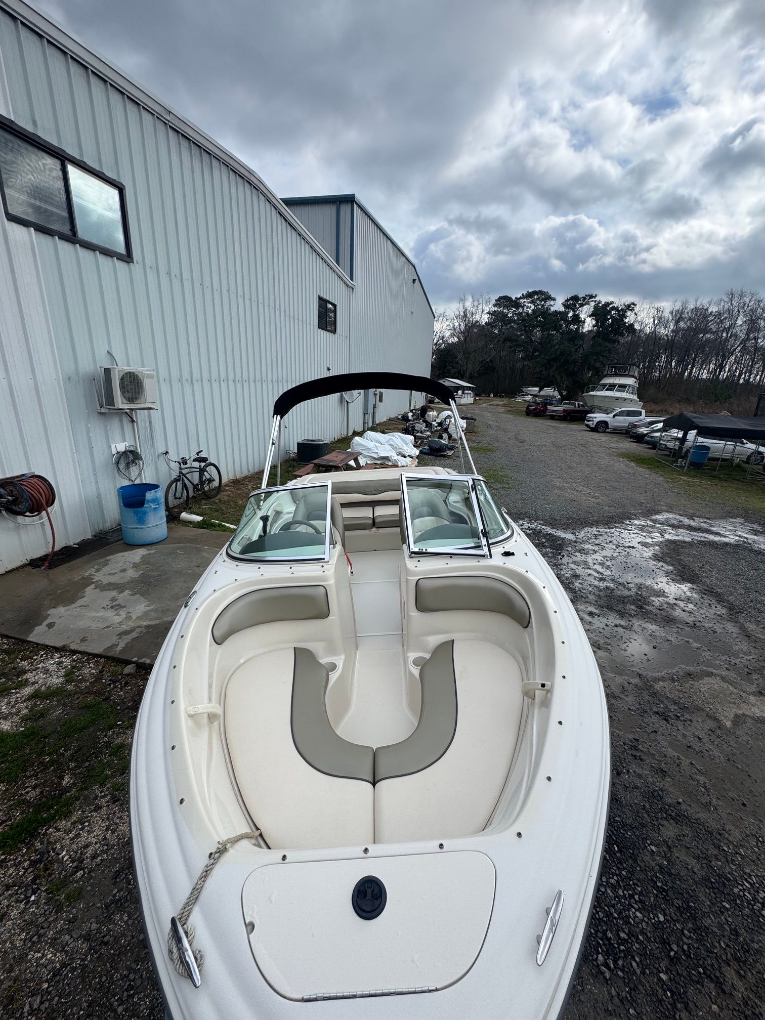 A 2005 Sea Ray 185 Sport is parked on a gravel lot beside a building.