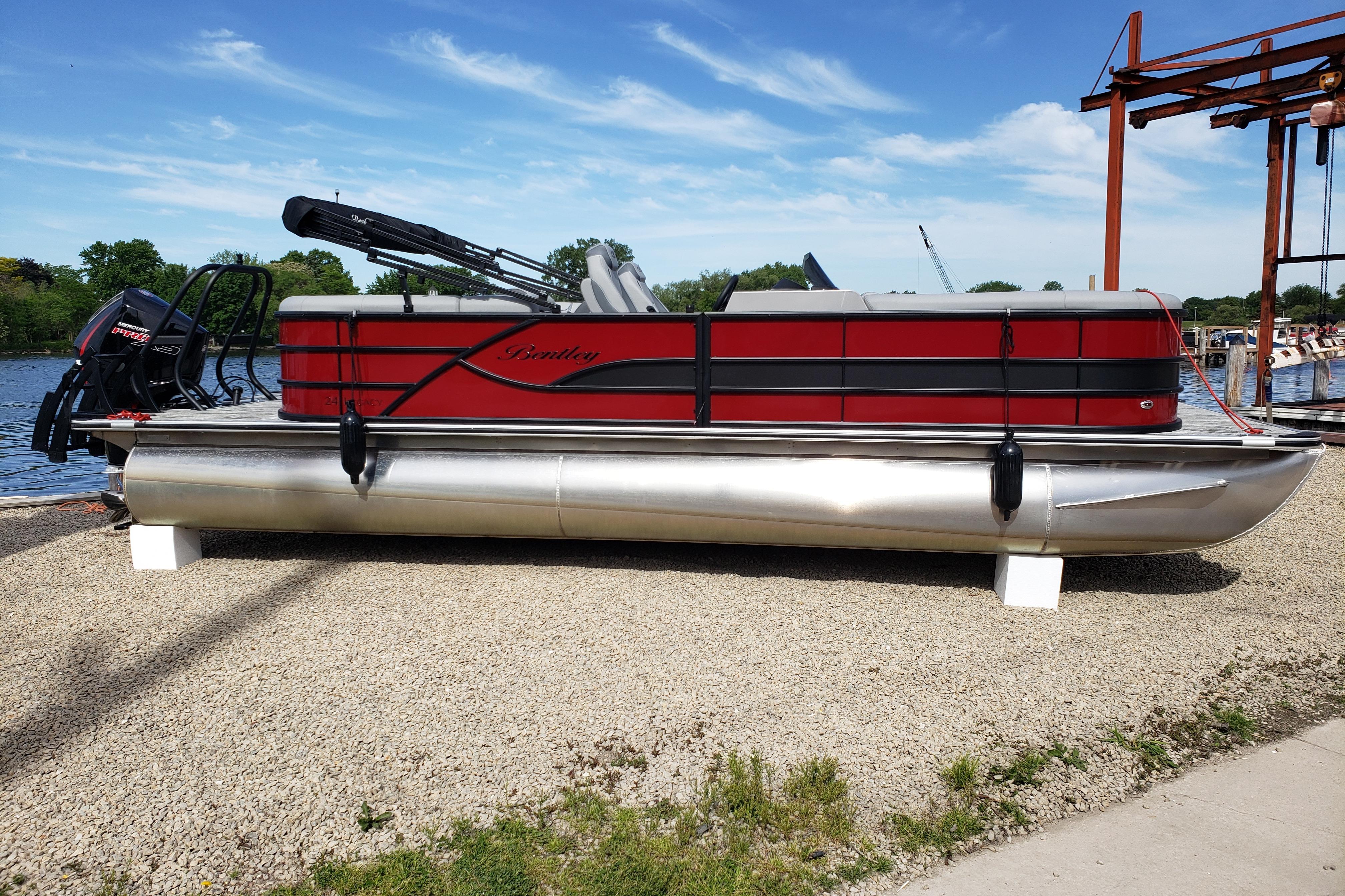 2026 Bentley Pontoons Legacy 243 Navigator Ext on display by a lakeside.
