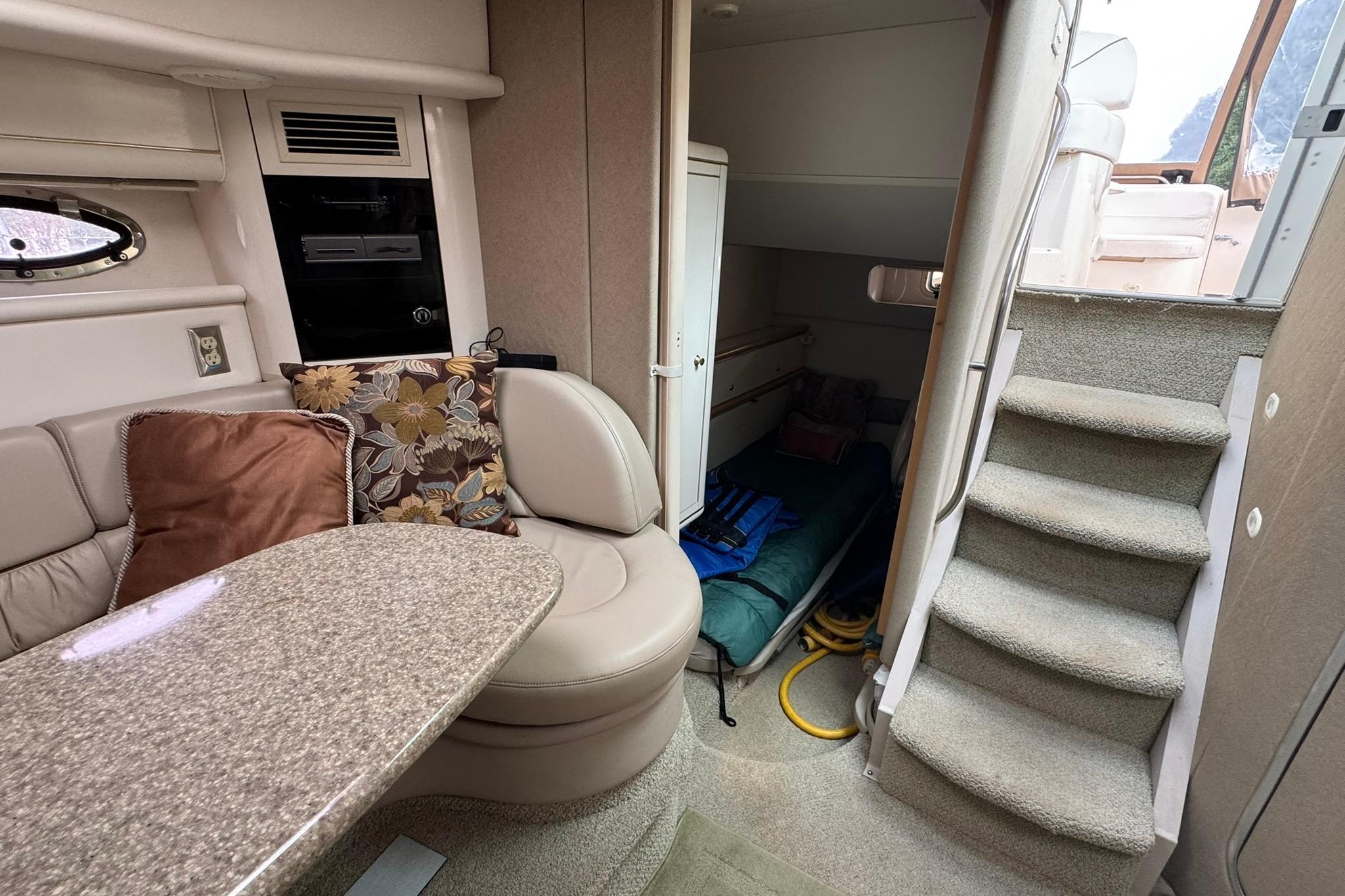 Interior of 1998 Maxum 3700 SCR yacht with seating, table, and stairs.