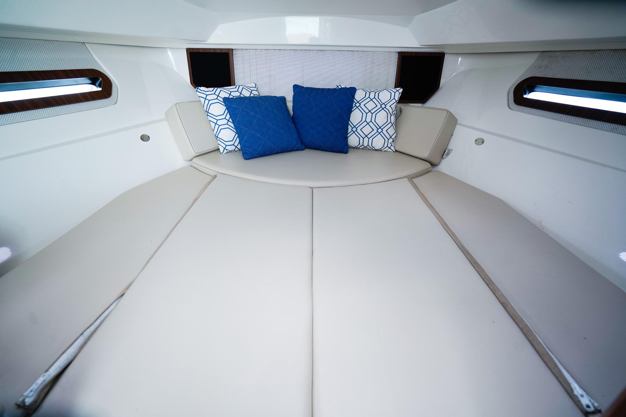 2020 Pursuit OS 325 Offshore cabin interior with cushioned seating and decorative pillows.