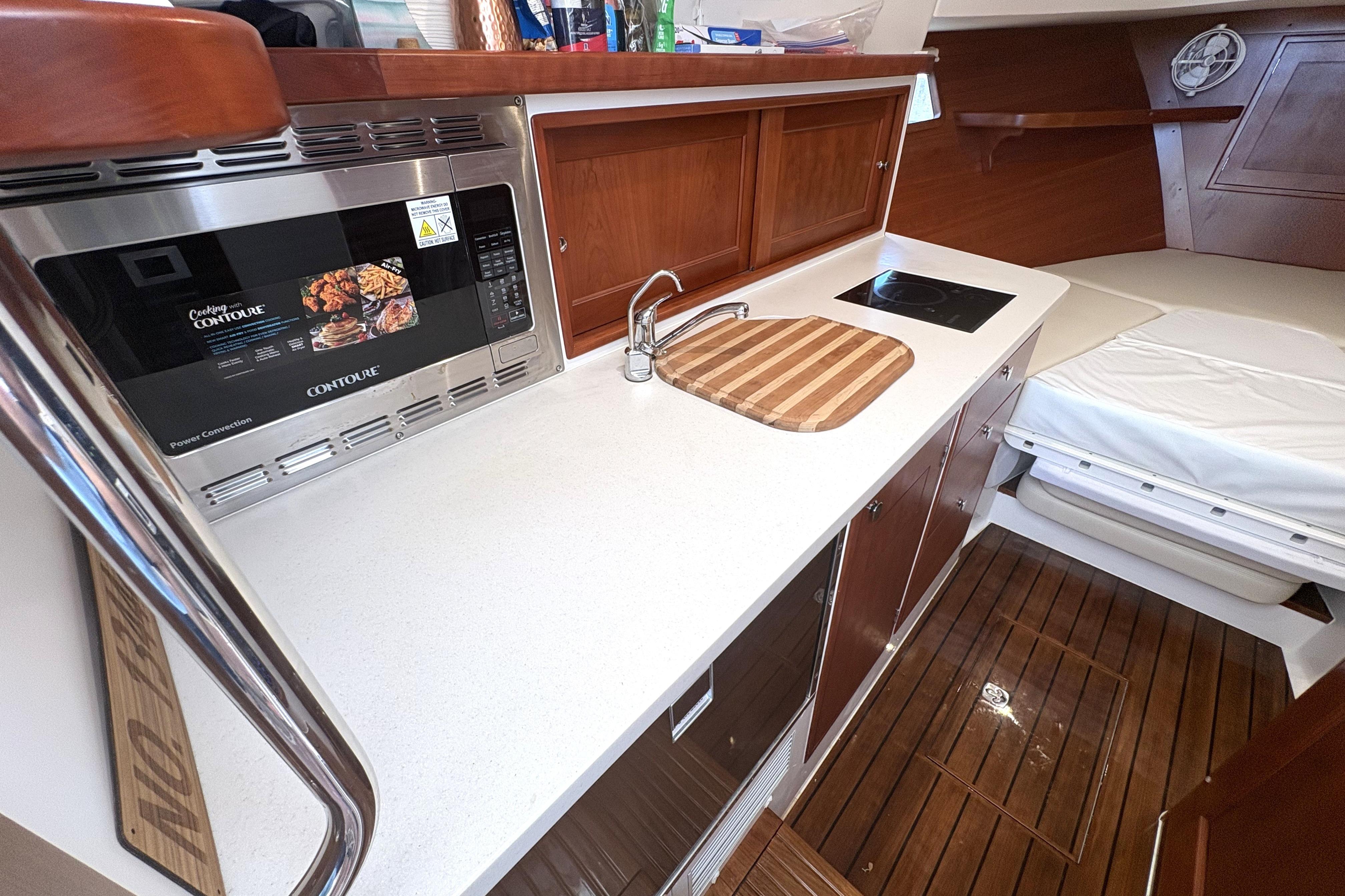 2024 MJM 35z yacht interior with kitchenette, featuring microwave, sink, and cooktop.