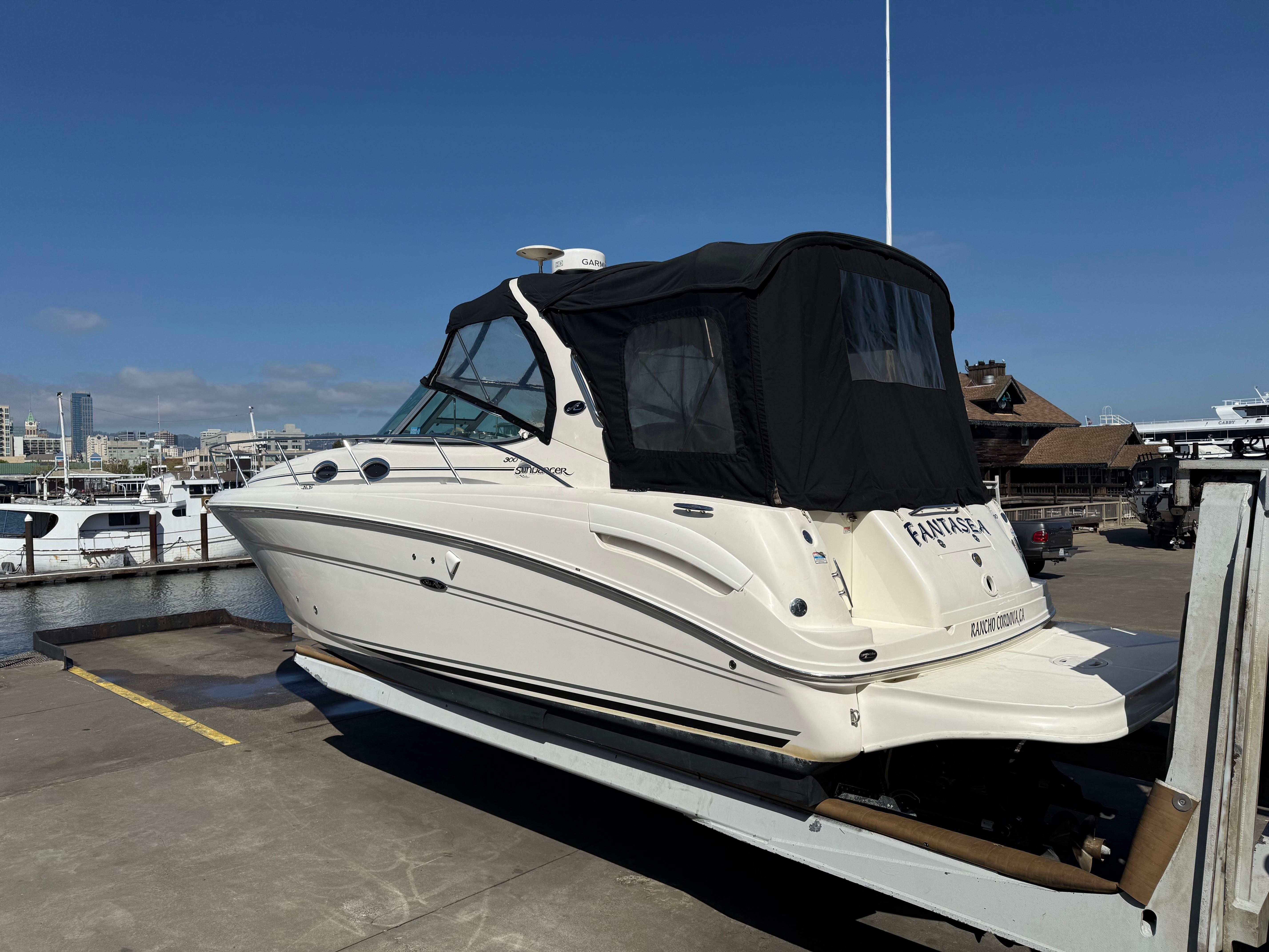 2004 Sea Ray 300 Sundancer boat docked at marina under clear blue sky.