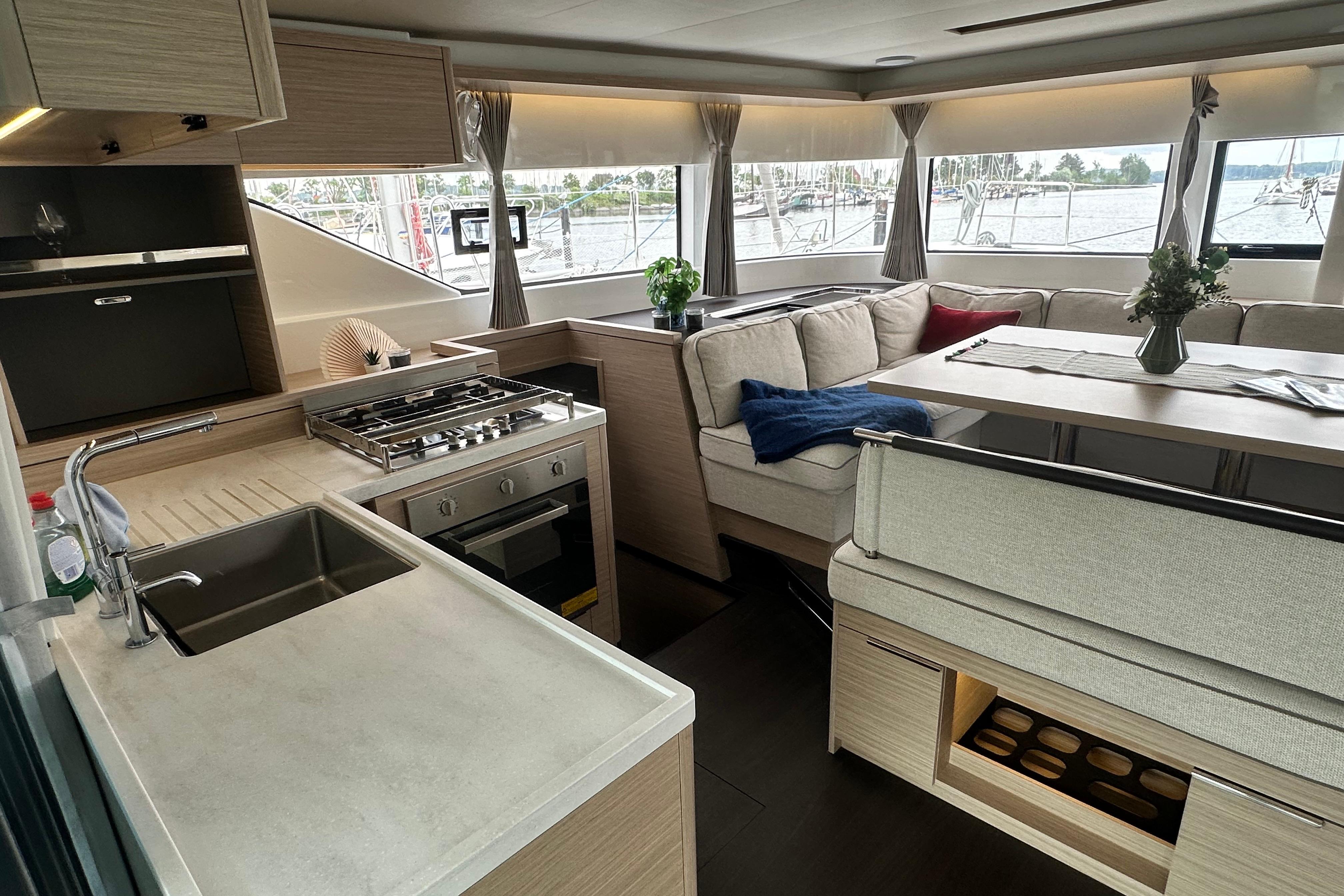 Luxurious interior of 2026 Lagoon 51 yacht with modern kitchen and cozy seating area.