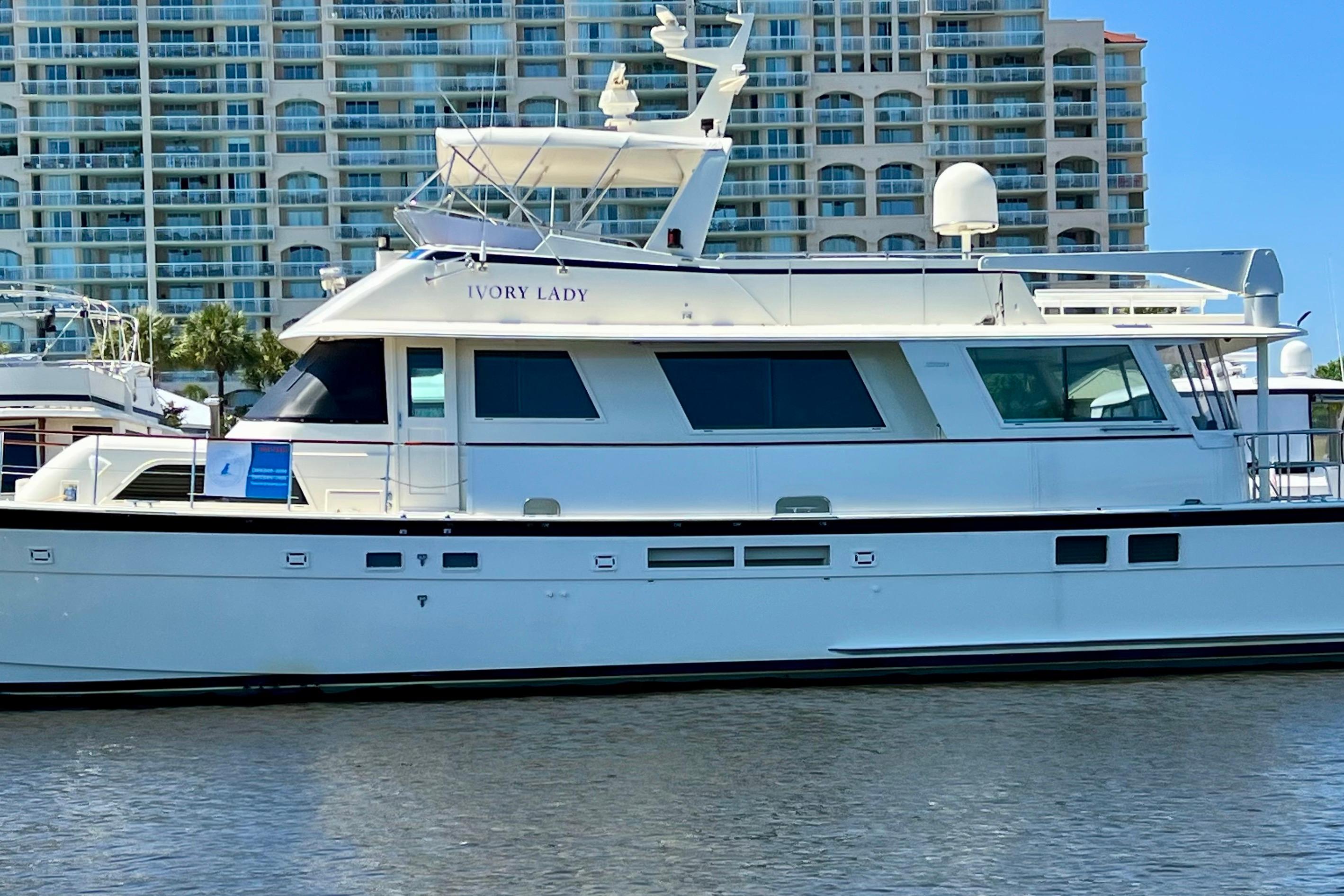1987 Hatteras 70 Cockpit Motor Yacht docked near modern high-rise buildings.