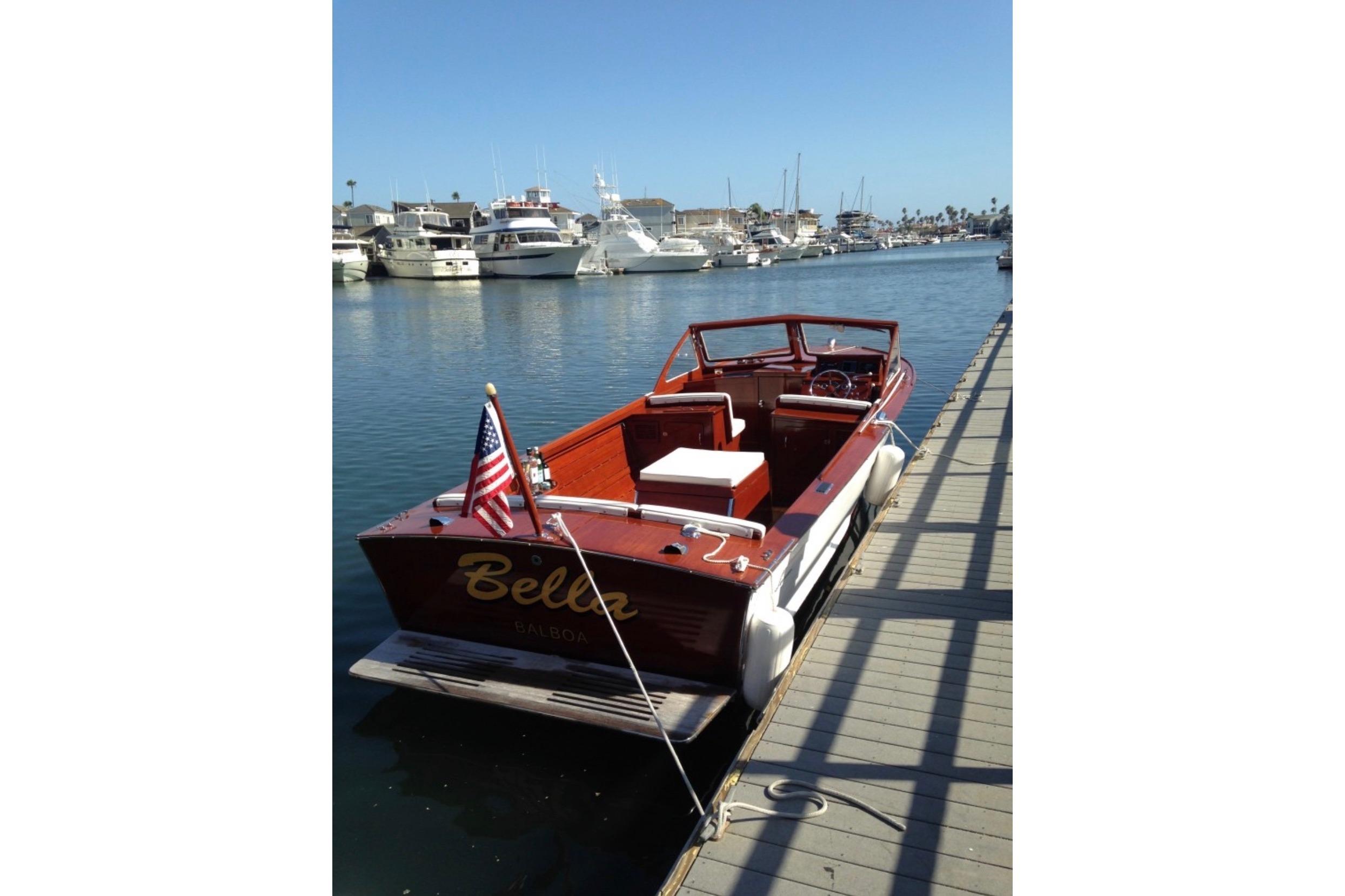 1964 Lyman 25 Sleeper boat docked in a marina, featuring classic wooden design.