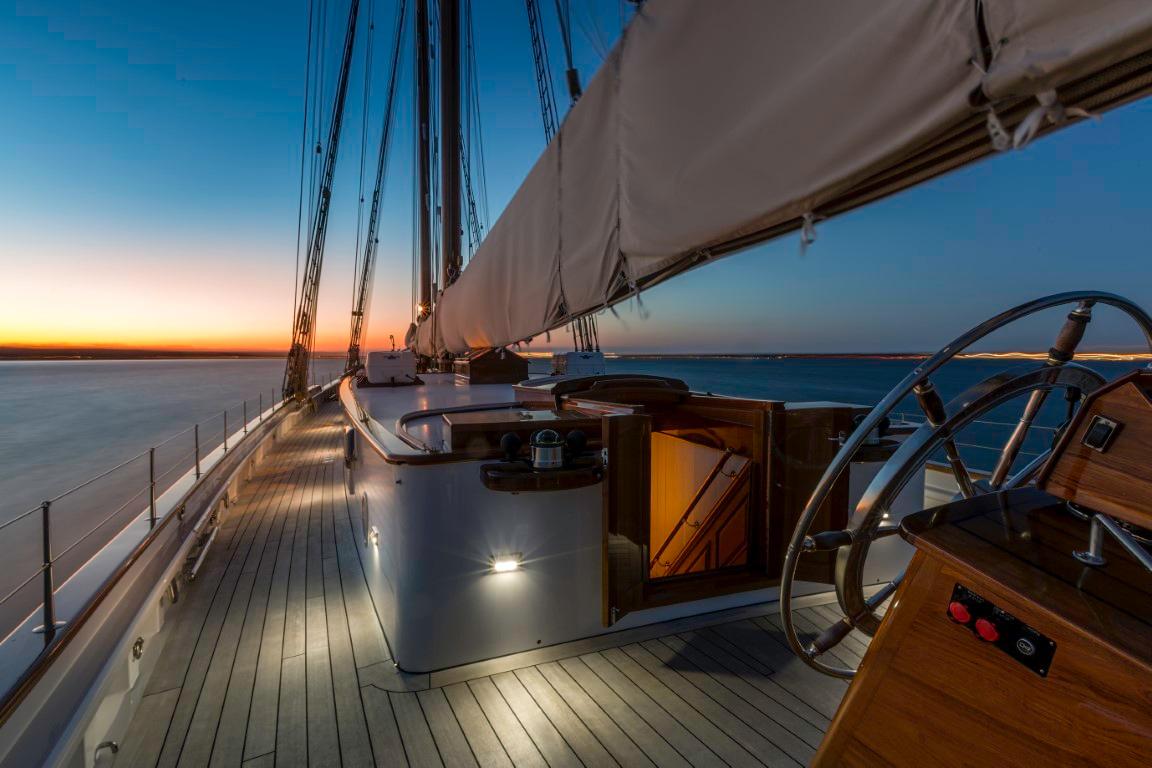 Elegant 2014 Eastern Shipbuilding Schooner at sunset, featuring a wooden deck and steering wheel.