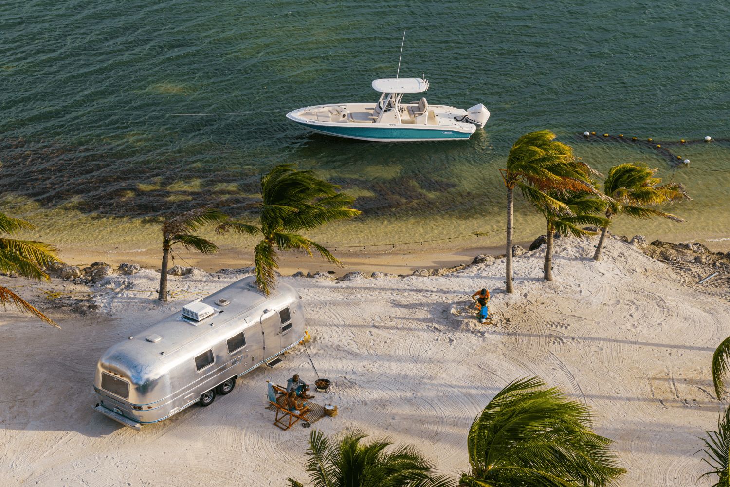 A Boston Whaler 25DA boat is anchored in clear water near a sandy beach.