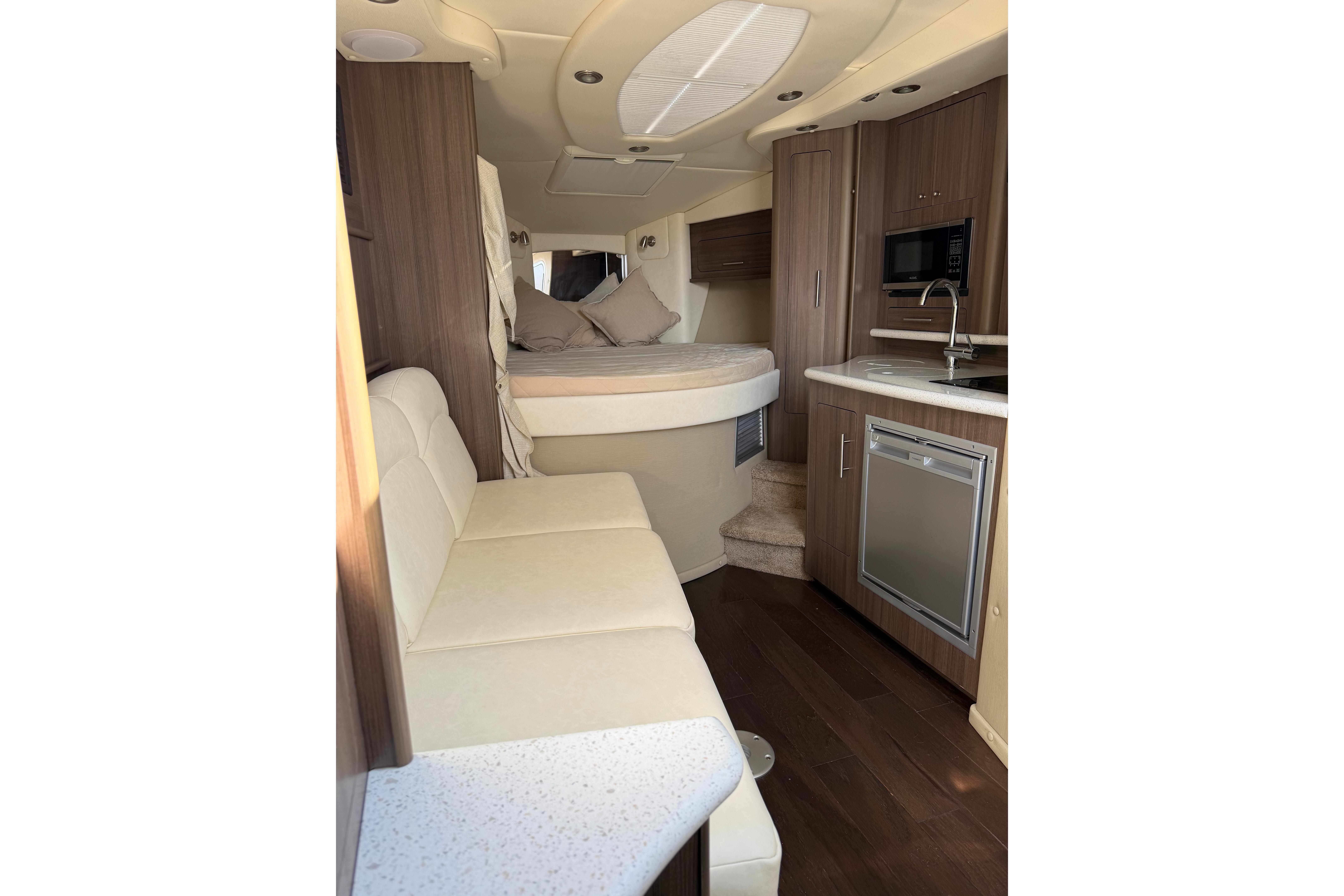 2019 Rinker EX 320 interior with kitchenette, seating, and bed. Luxurious boat cabin design.