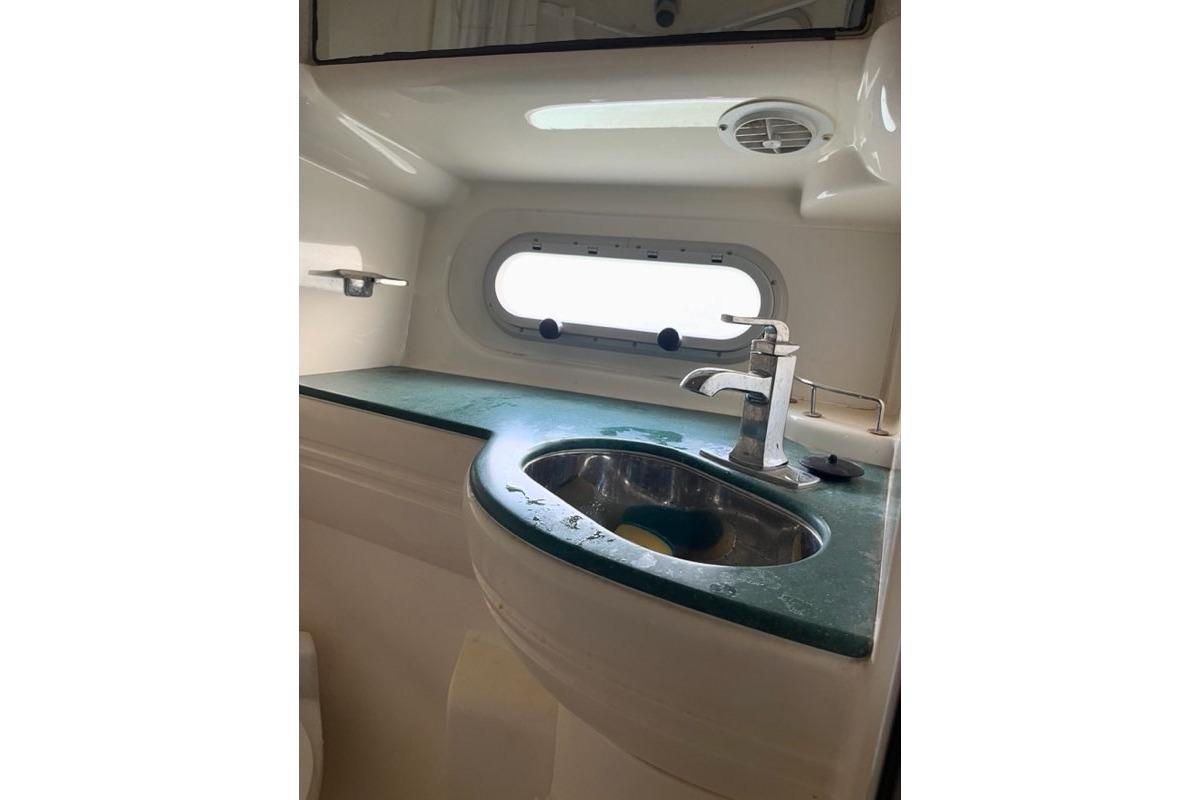 Bathroom sink area in a 1999 Sealine F44 yacht, featuring a modern faucet and oval window.