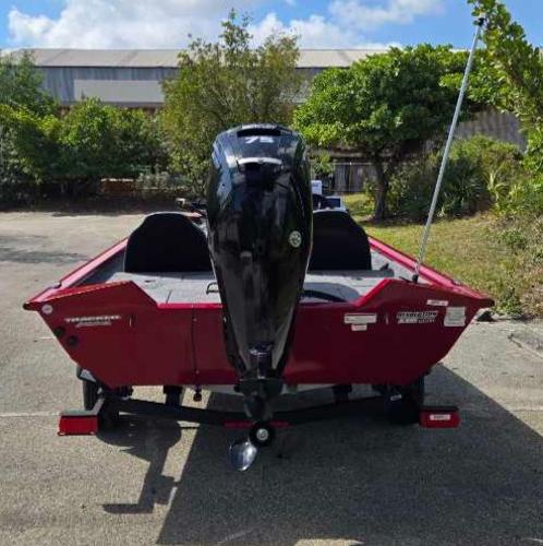 2025 Tracker Pro Team 175 boat, red exterior, parked outdoors, rear view.