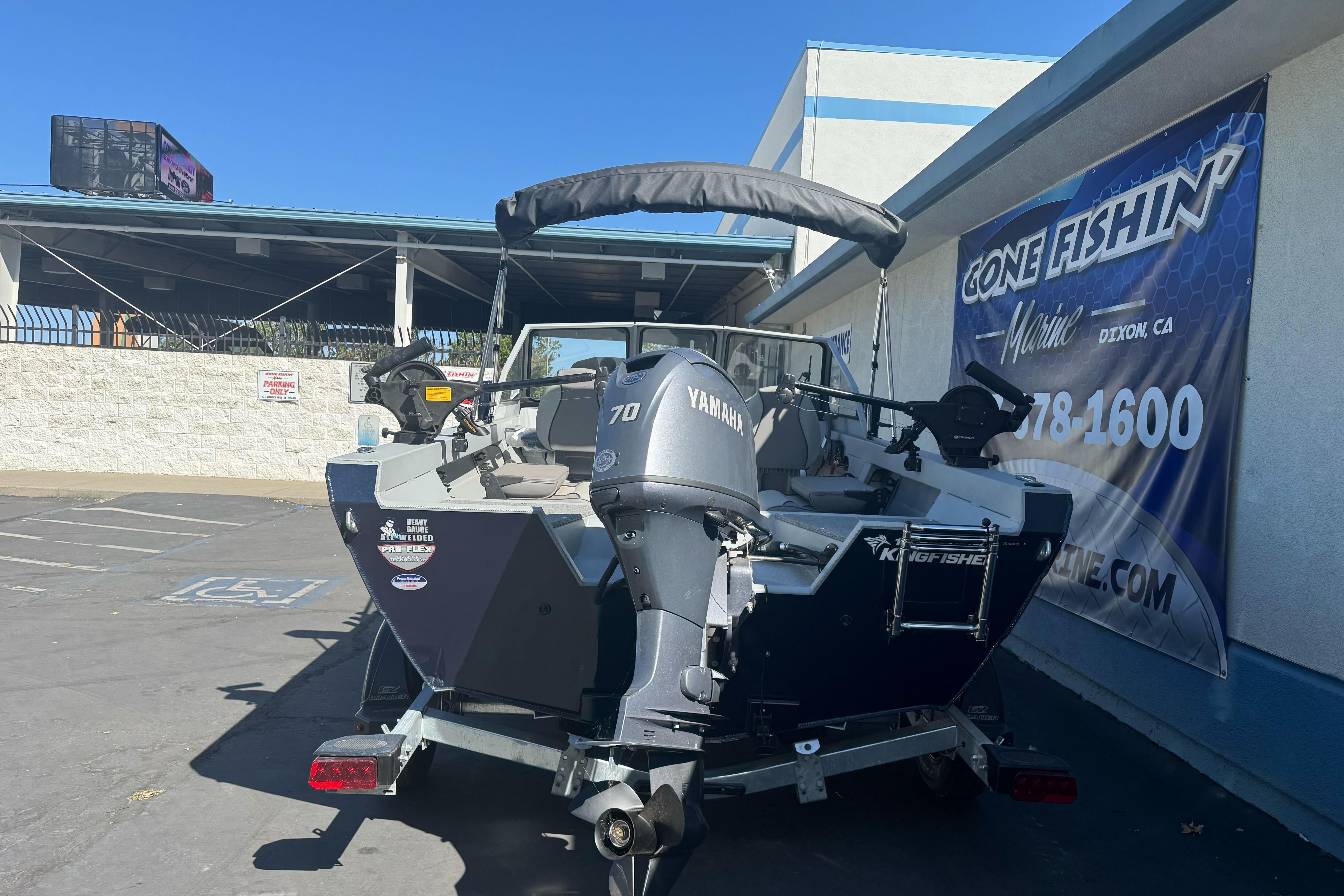 2026 KingFisher 16 Falcon boat with Yamaha motor parked outside marine shop.