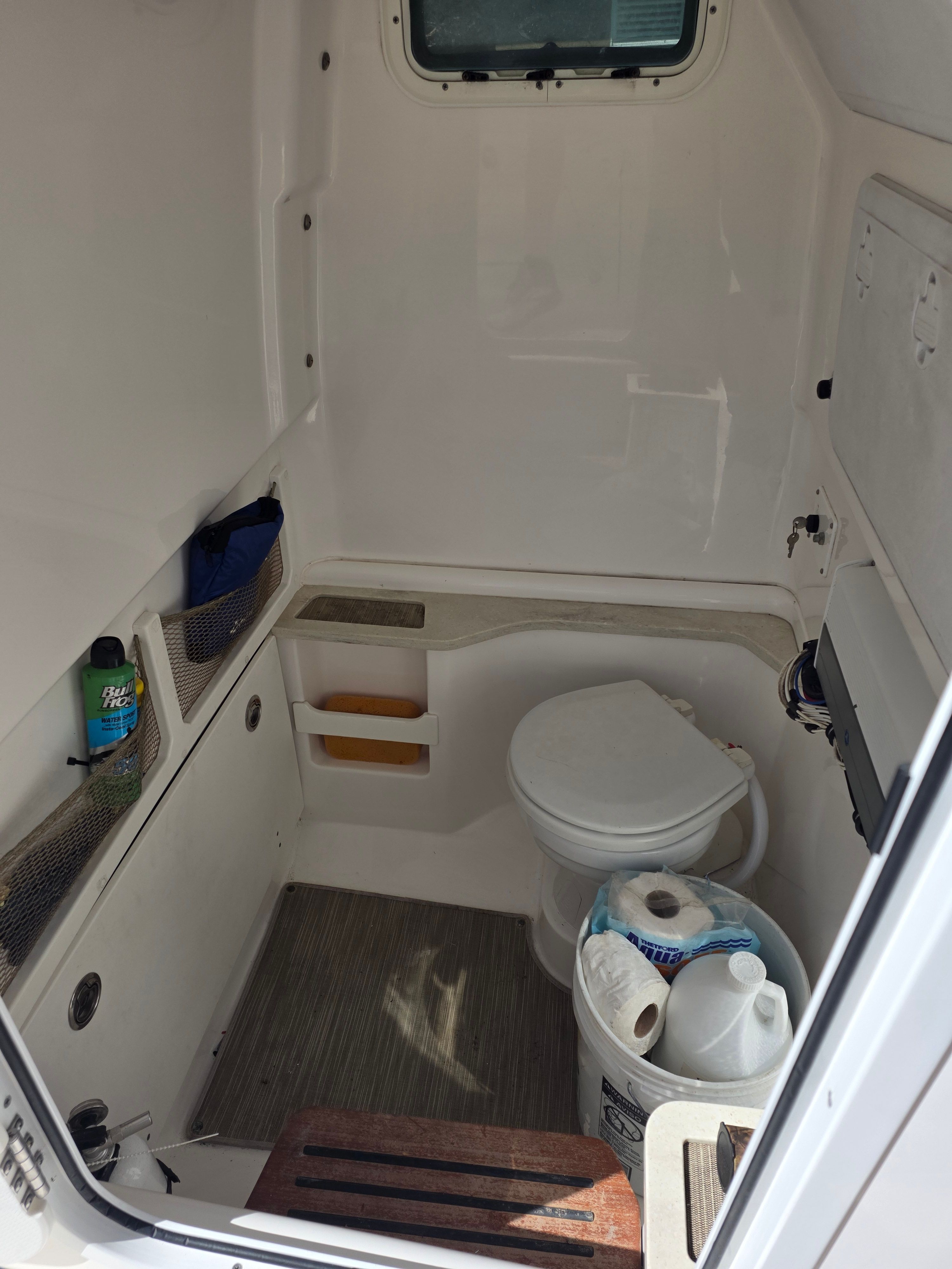 Interior of a 2017 Everglades 273 Center Console with a toilet and storage space.
