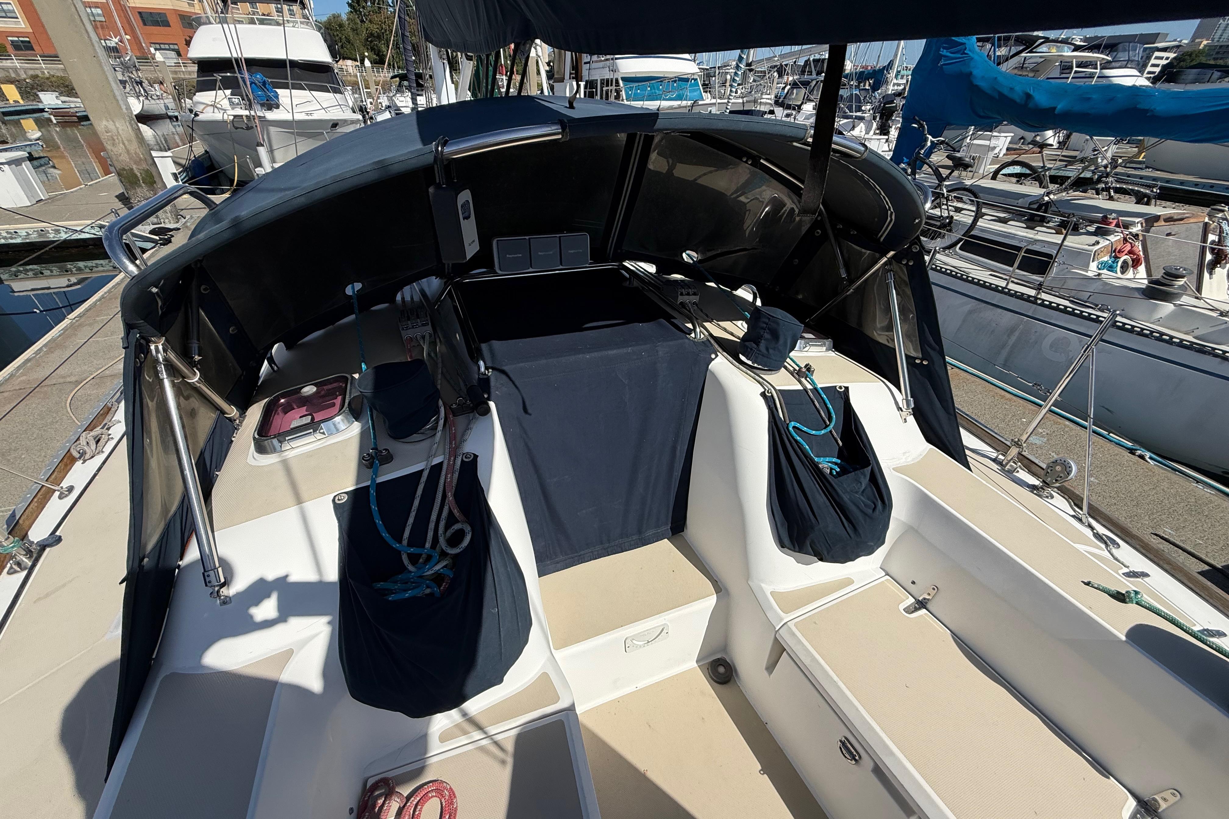 Cockpit of 2004 Sabre 386 sailboat docked at marina, featuring ropes and seating area.