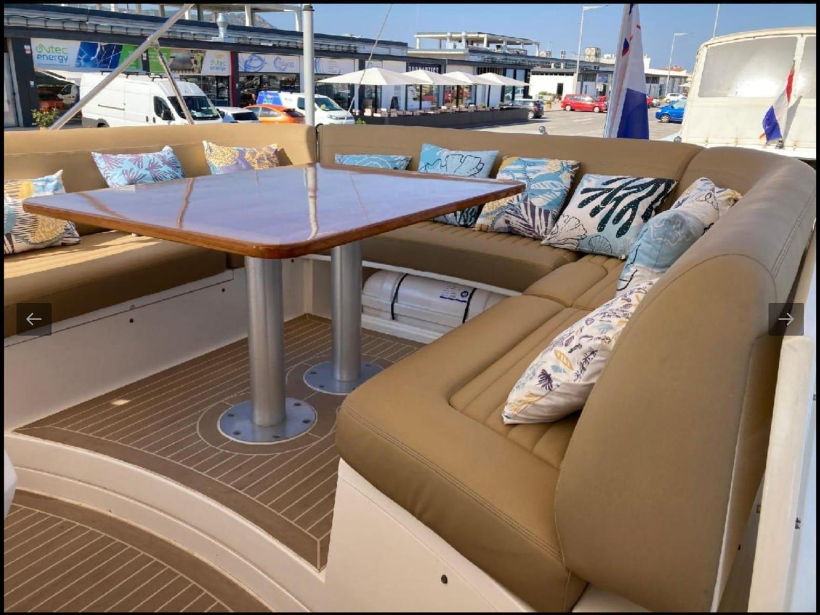 Luxurious seating area on a 2005 Sealine T60 yacht with plush cushions and a wooden table.