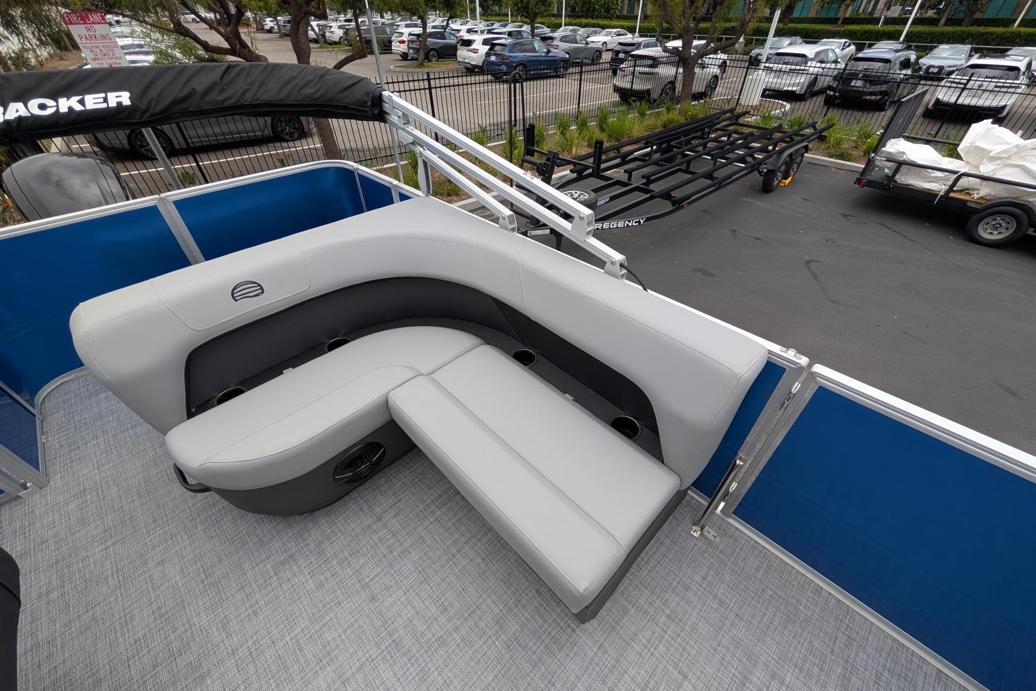 2026 Sun Tracker Party Barge 18 DLX with gray seating and blue paneling, parked outdoors.