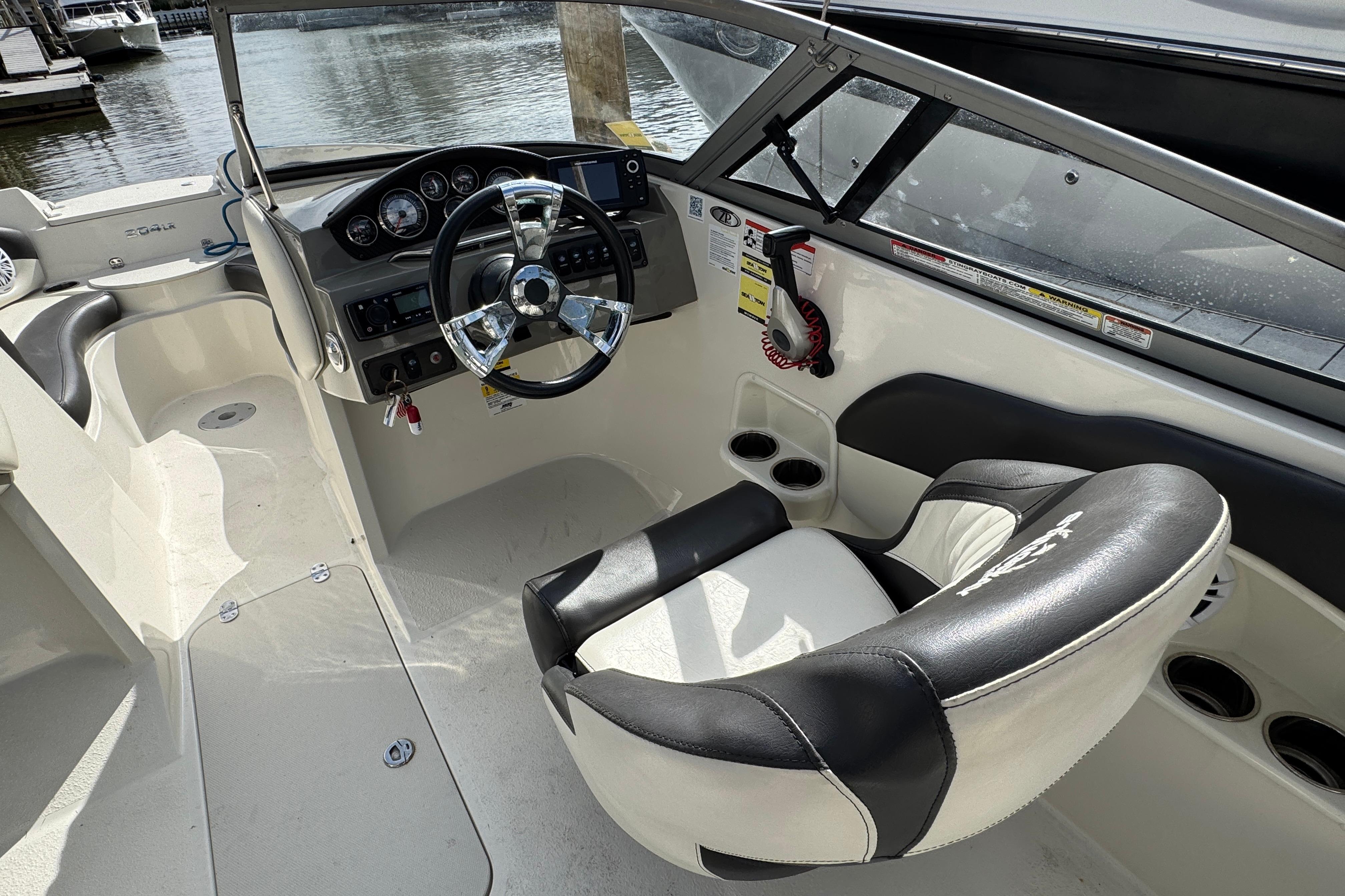 2019 Stingray 204 LR boat interior with steering wheel and dashboard, docked by the water.