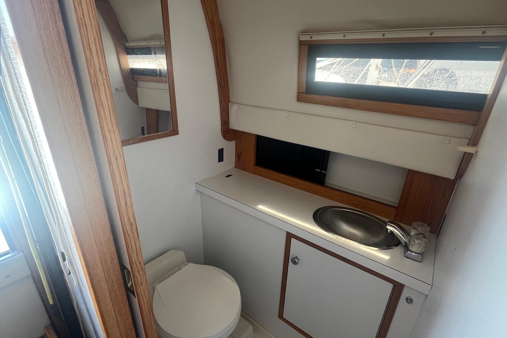 1988 Seafox 29 Flybridge boat bathroom with sink, toilet, and window.