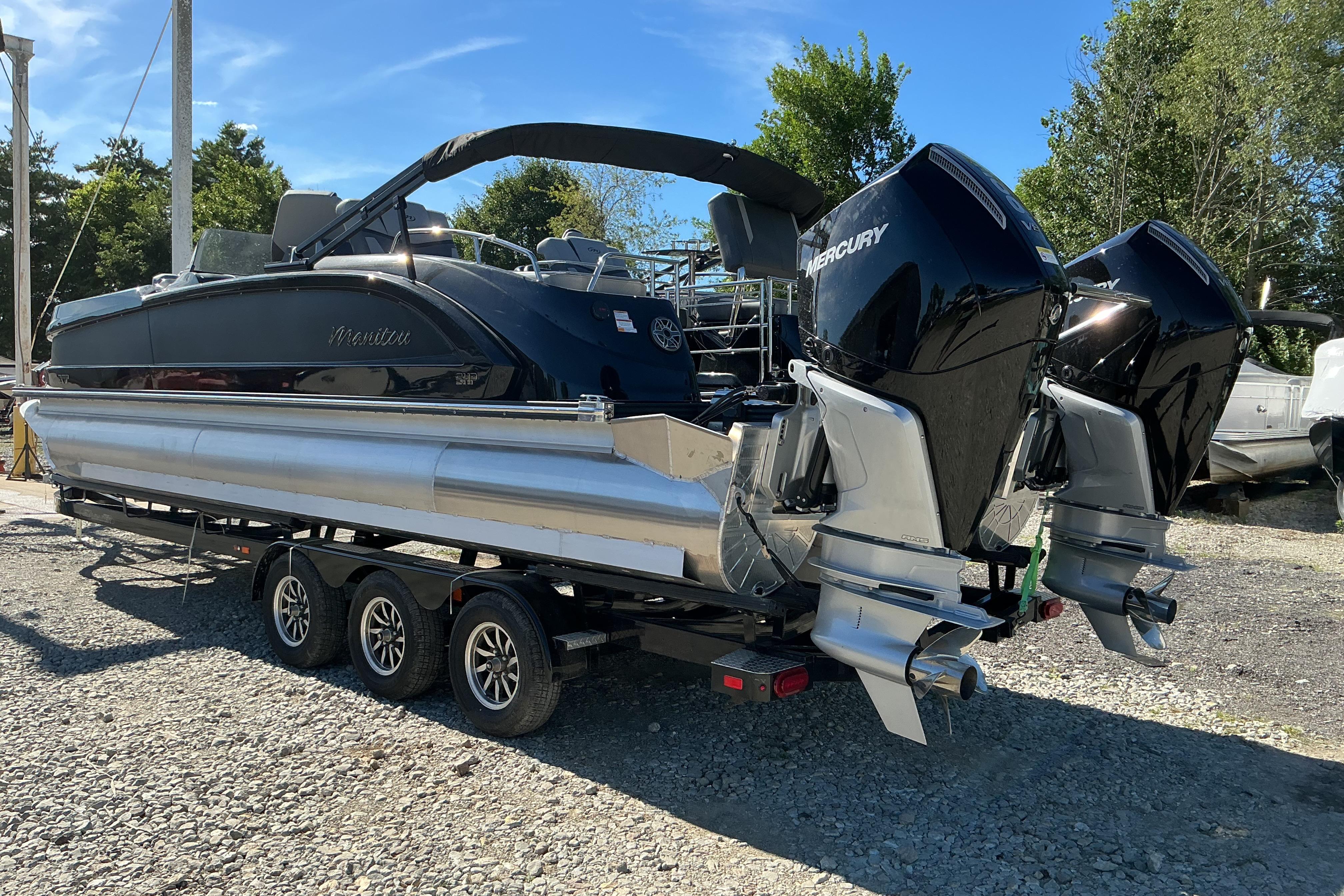 2024 Manitou 25 X-Plode XT SRS pontoon boat with dual Mercury engines on trailer.