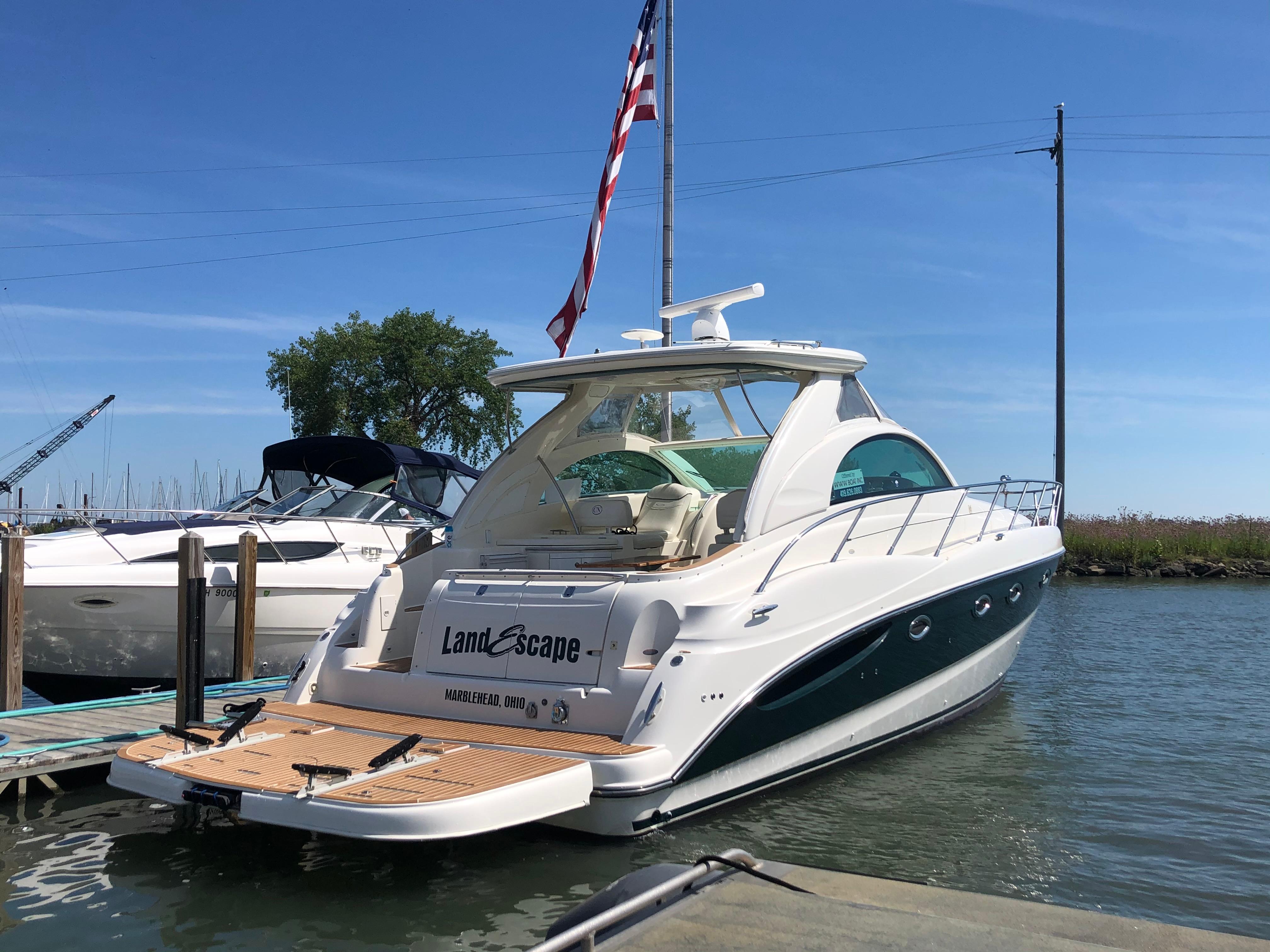 2002 Maxum 4200 SCR yacht docked with American flag, clear sky background.
