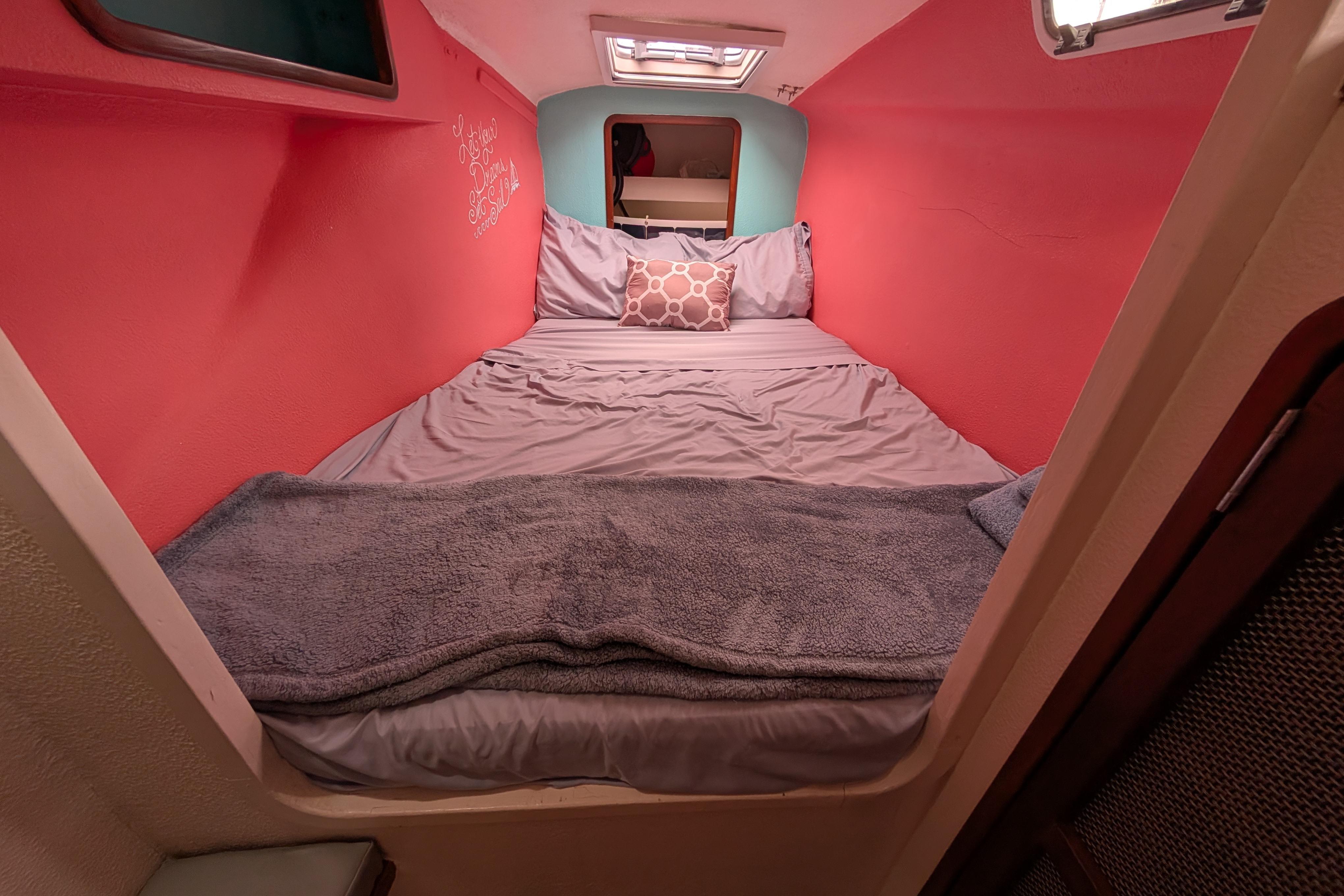 Cozy cabin interior of 1999 Island Spirit 37 sailboat with vibrant red walls and comfortable bedding.