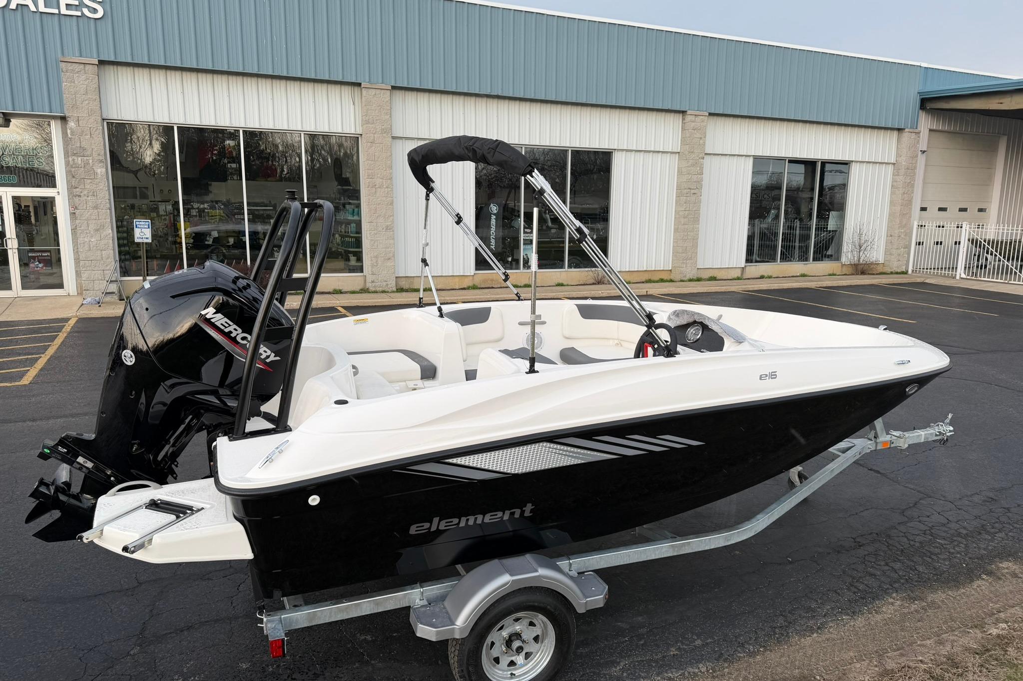 2026 Bayliner Element E16 boat on trailer, parked outside a sales building.