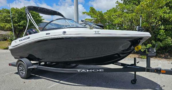 2025 Tahoe 185 S boat on trailer, parked outdoors, surrounded by greenery.