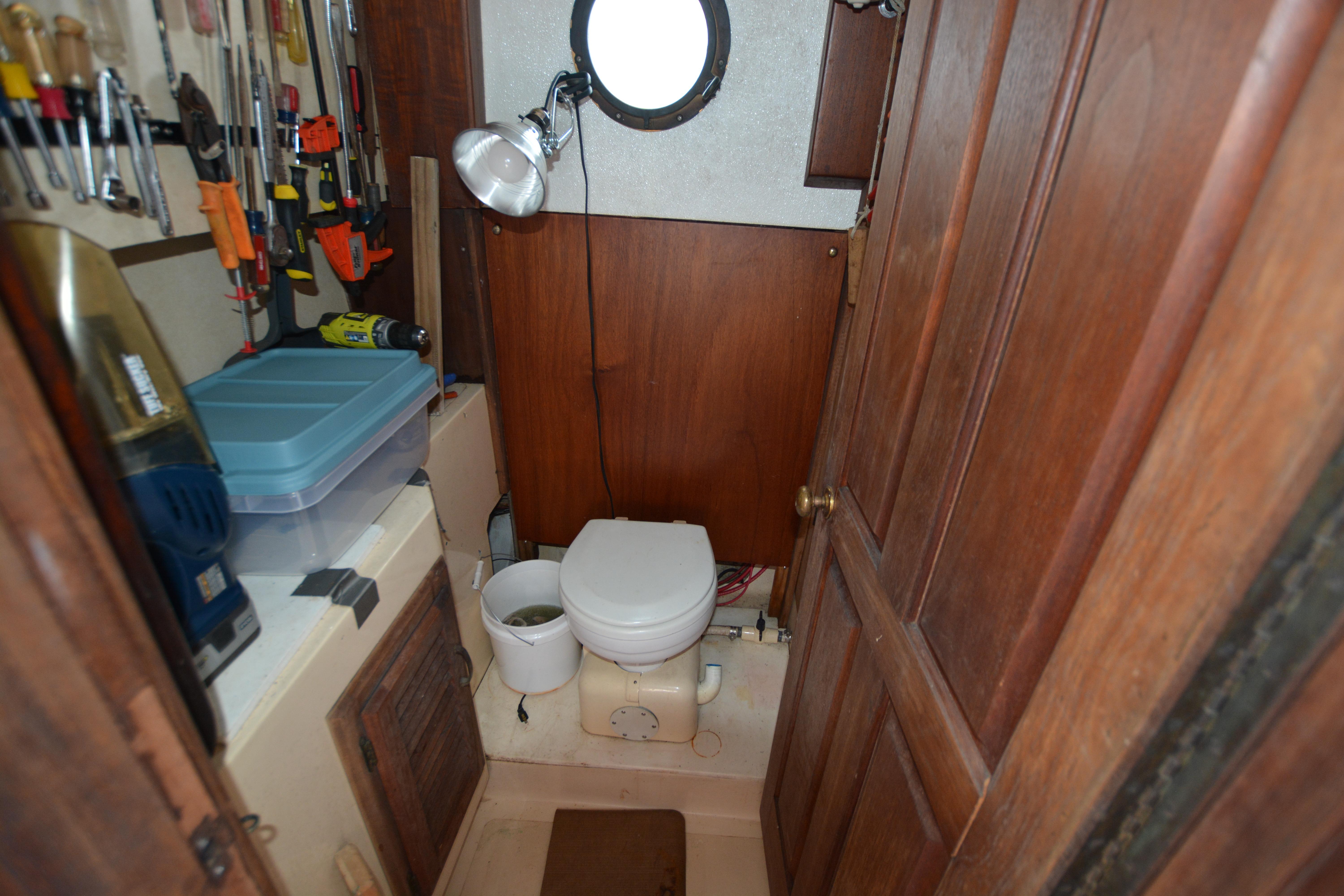 1974 Fales Navigator boat bathroom with tools and wooden cabinetry.